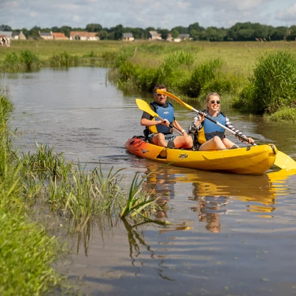 couple qui fait du kayak dans les marais du parc régional naturel des marais du cotentin et du bessin, kayak et pagaies jaunes, eau calme, nature verdoyante, tourisme écologique, aventure en pleine nature,