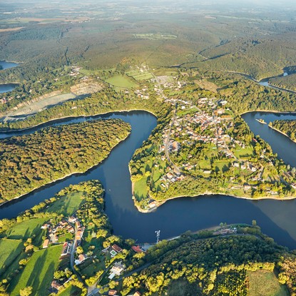 Vue du ciel sur l’imposante forêt verte de Mervent avec le lac qui entoure les habitations
