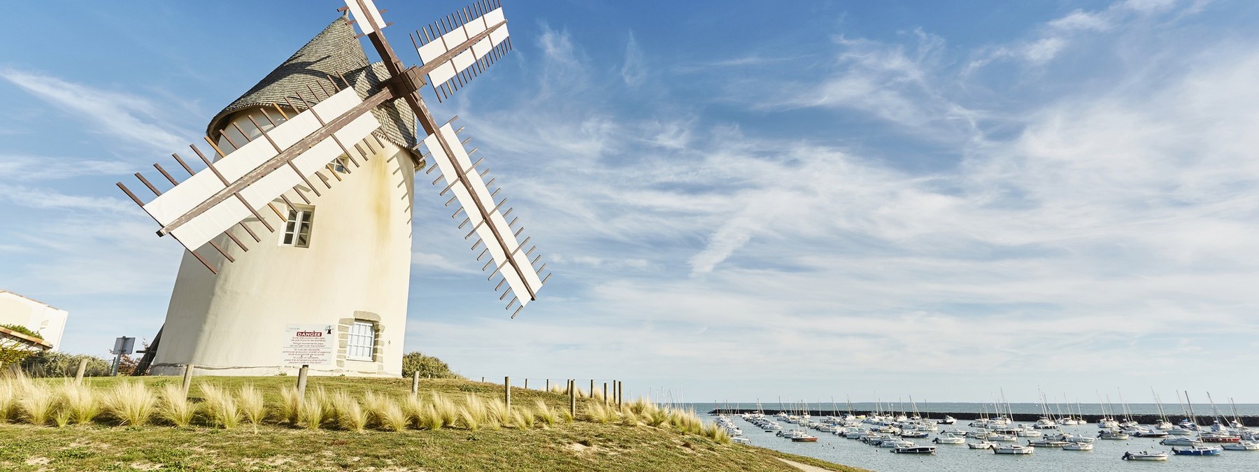 Moulin de Jard sur Mer sous un beau ciel bleu à côté du port avec des bateaux amarrés