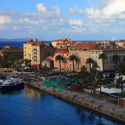 Vue panoramique d’Ajaccio, capitale de la Corse-du-Sud, entre mer et montagne. Le port, les façades colorées et la cathédrale se dévoilent sous une lumière dorée, reflet de la douceur méditerranéenne et du charme authentique de la cité impériale.