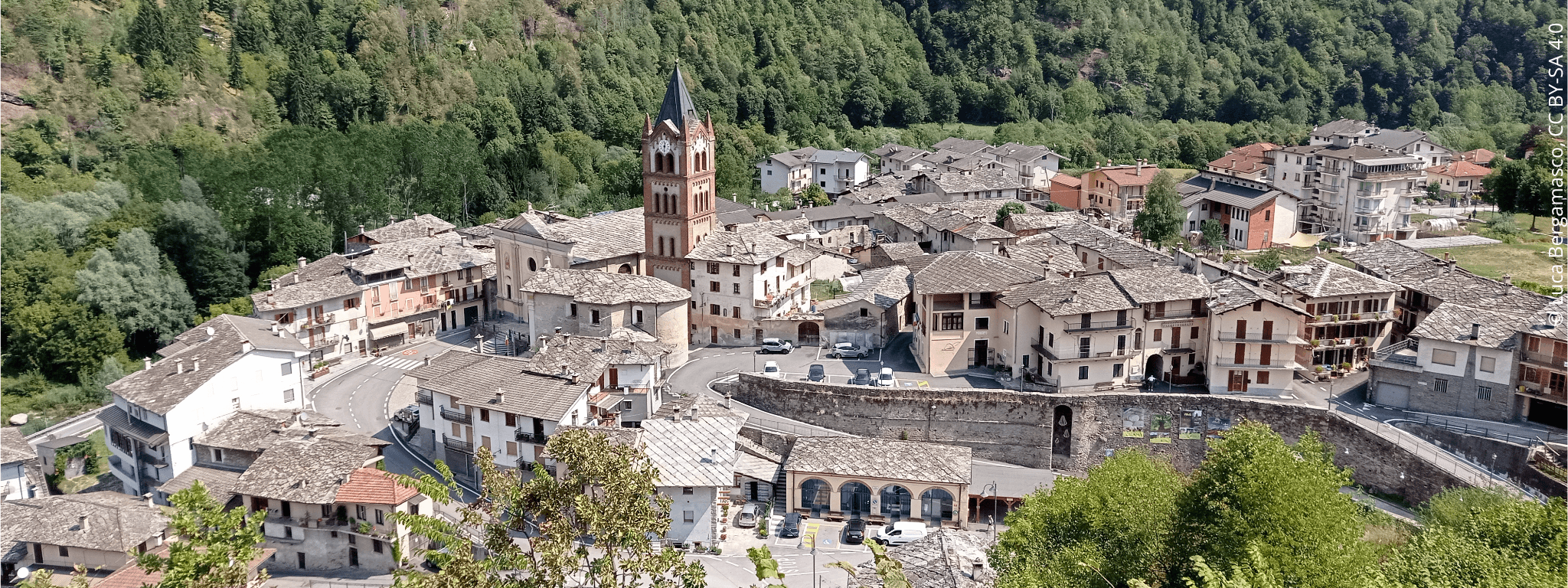 Vue d’en haut sur le la commune de Melle avec des habitations, un clocher et une vaste forêt boisée qui s’étend au fond.