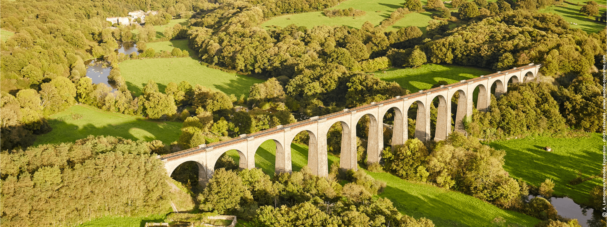 Vue aérienne sur la campagne du bocage avec des champs et arbres verts, surplombée par le Viaduc passant sur la rivière de la Sèvre Nantaise.