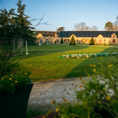 Haras de Saint-Lô, écuries, bâtiments historiques, lumière du matin avec le soleil, pelouses et fleurs
