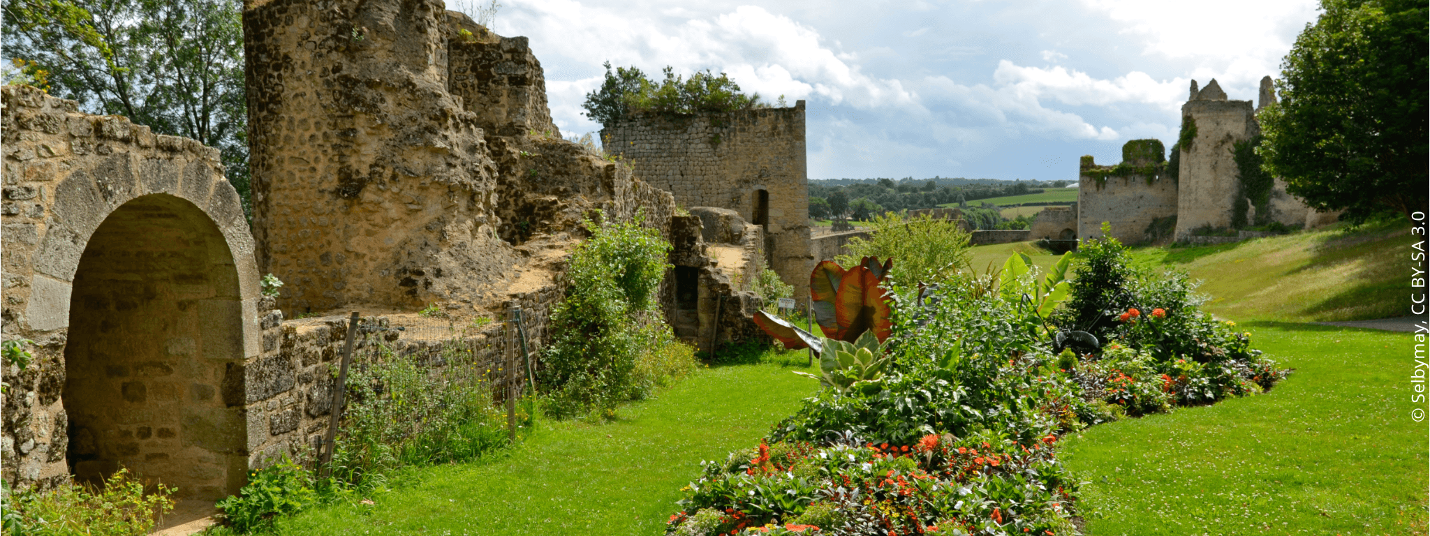 Pelouse verte avec par terre fleurie devant les vestiges du château de Bressuire 