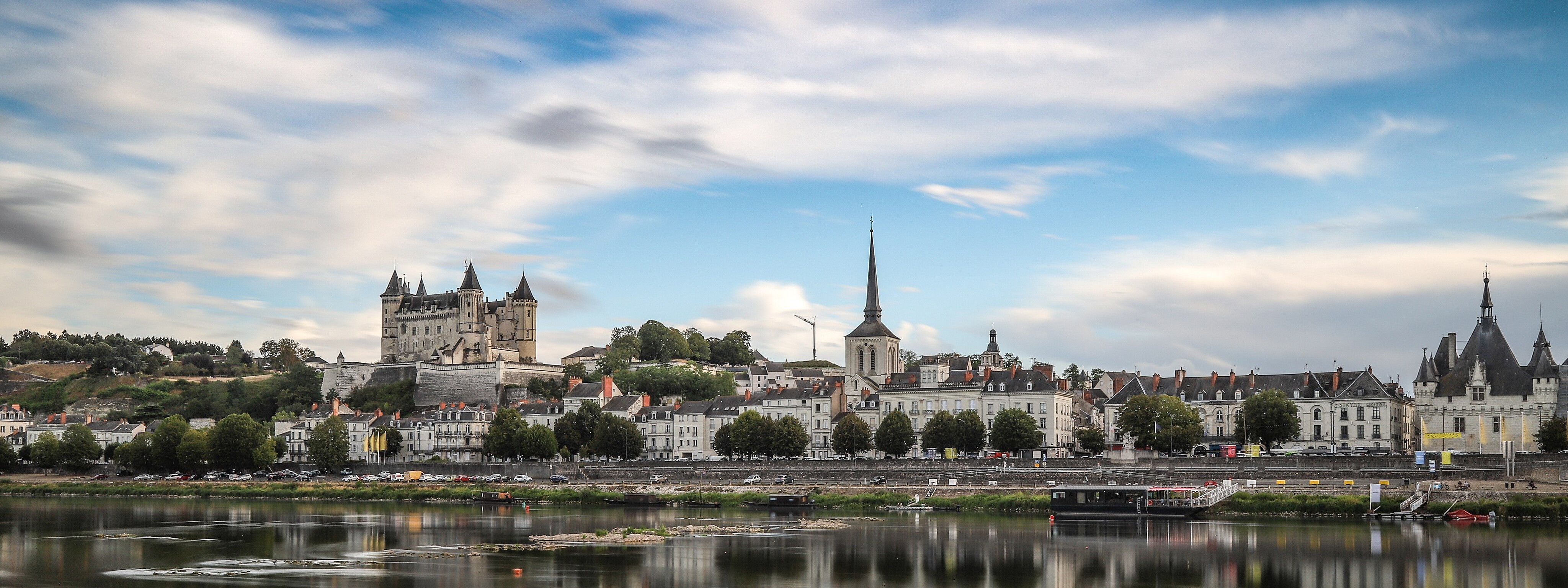 Vue depuis la Loire sur la ville de Saumur avec ses habitations, son château et le clocher d'une église