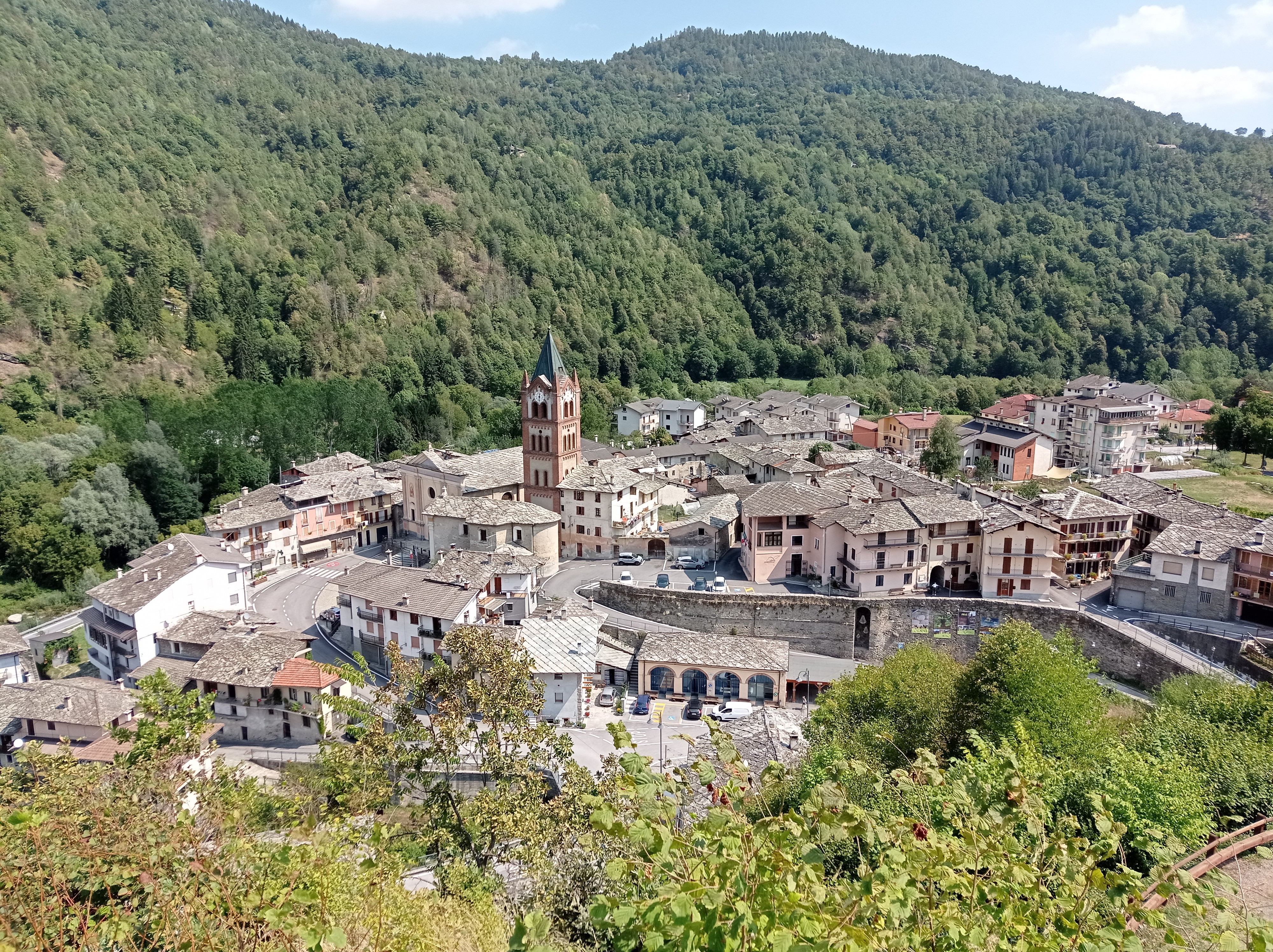 Vue d’en haut sur le la commune de Melle avec des habitations, un clocher et une vaste forêt boisée qui s’étend au fond.