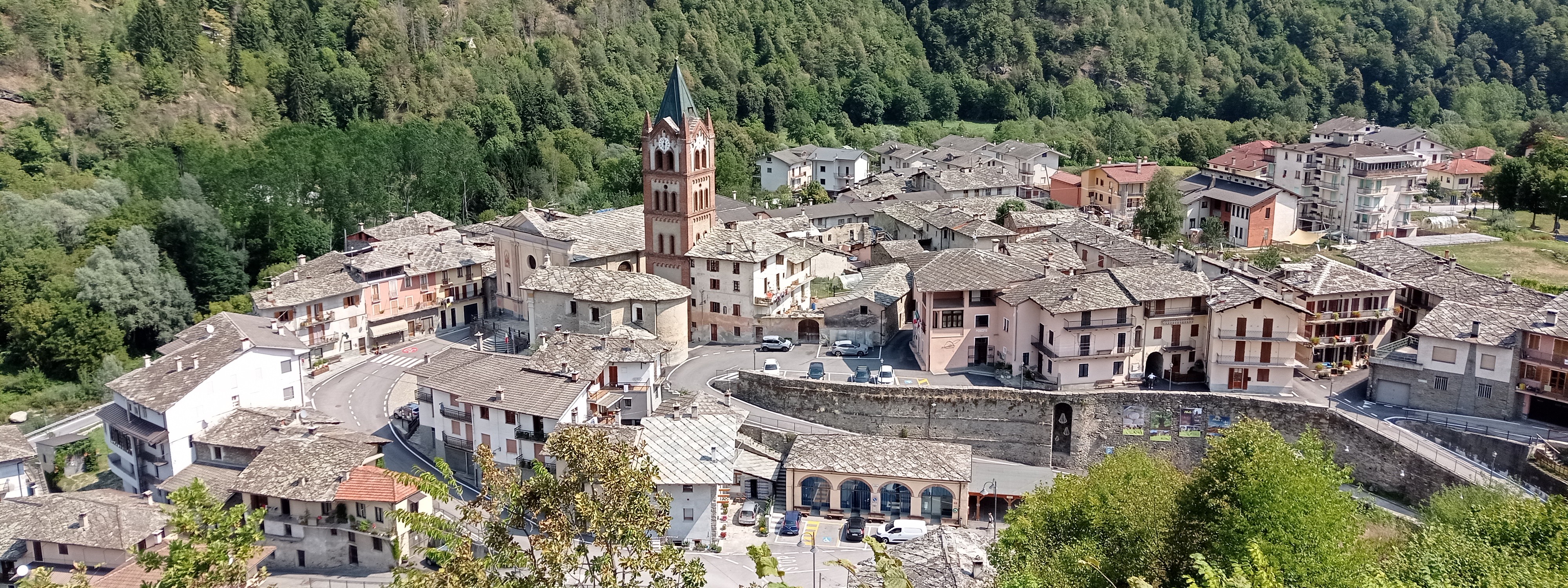 Vue d’en haut sur le la commune de Melle avec des habitations, un clocher et une vaste forêt boisée qui s’étend au fond.
