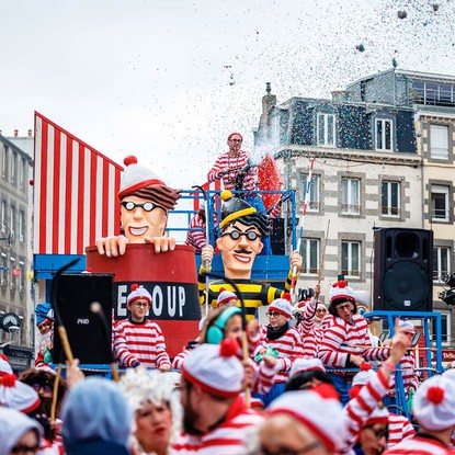 Char du Carnaval de Granville représentant des personnages humoristiques avec confettis en arrière-plan.