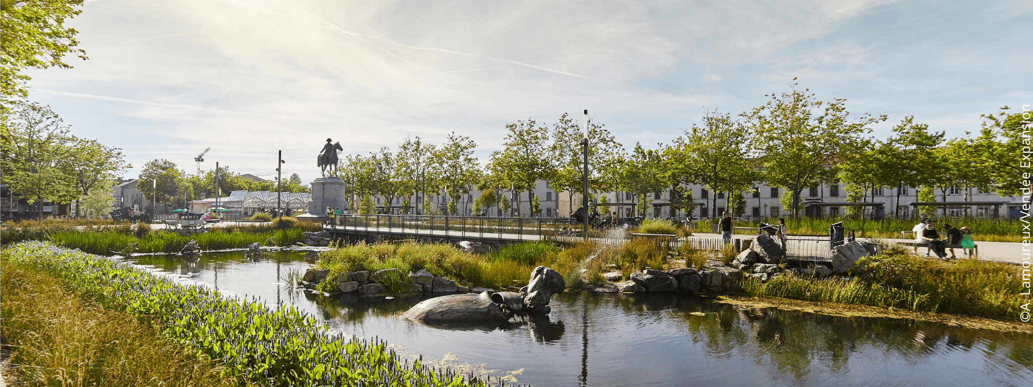 Vue sur les bassins entourés de verdure et les animaux mécaniques de la place Napoléon