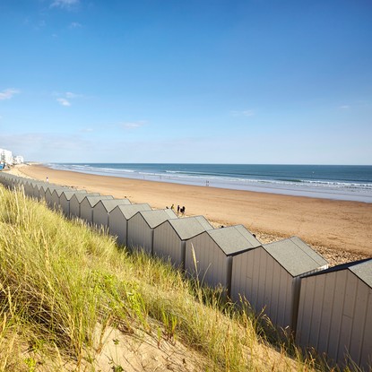Depuis les dunes sauvages, vue sur la grande plage de Saint Gilles Croix de vie avec les cabanes de plage sous un beau ciel bleu - A. Lamoureux/Vendée Expansion - droits réservés - www.vendee-tourisme.com / toute reproduction ou publication interdite