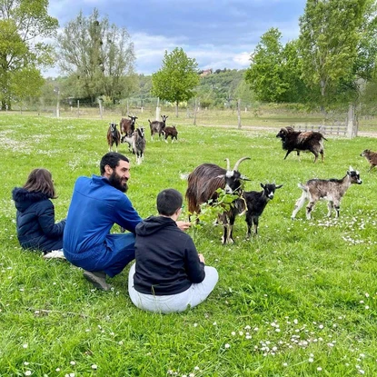Famille profitant d'un moment paisible entourée de chèvres et de moutons dans une ferme écologique.