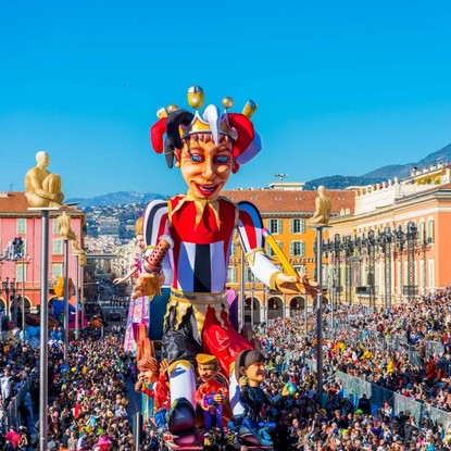 Vue du Carnaval de Nice en plein jour avec un char coloré et une foule joyeuse.