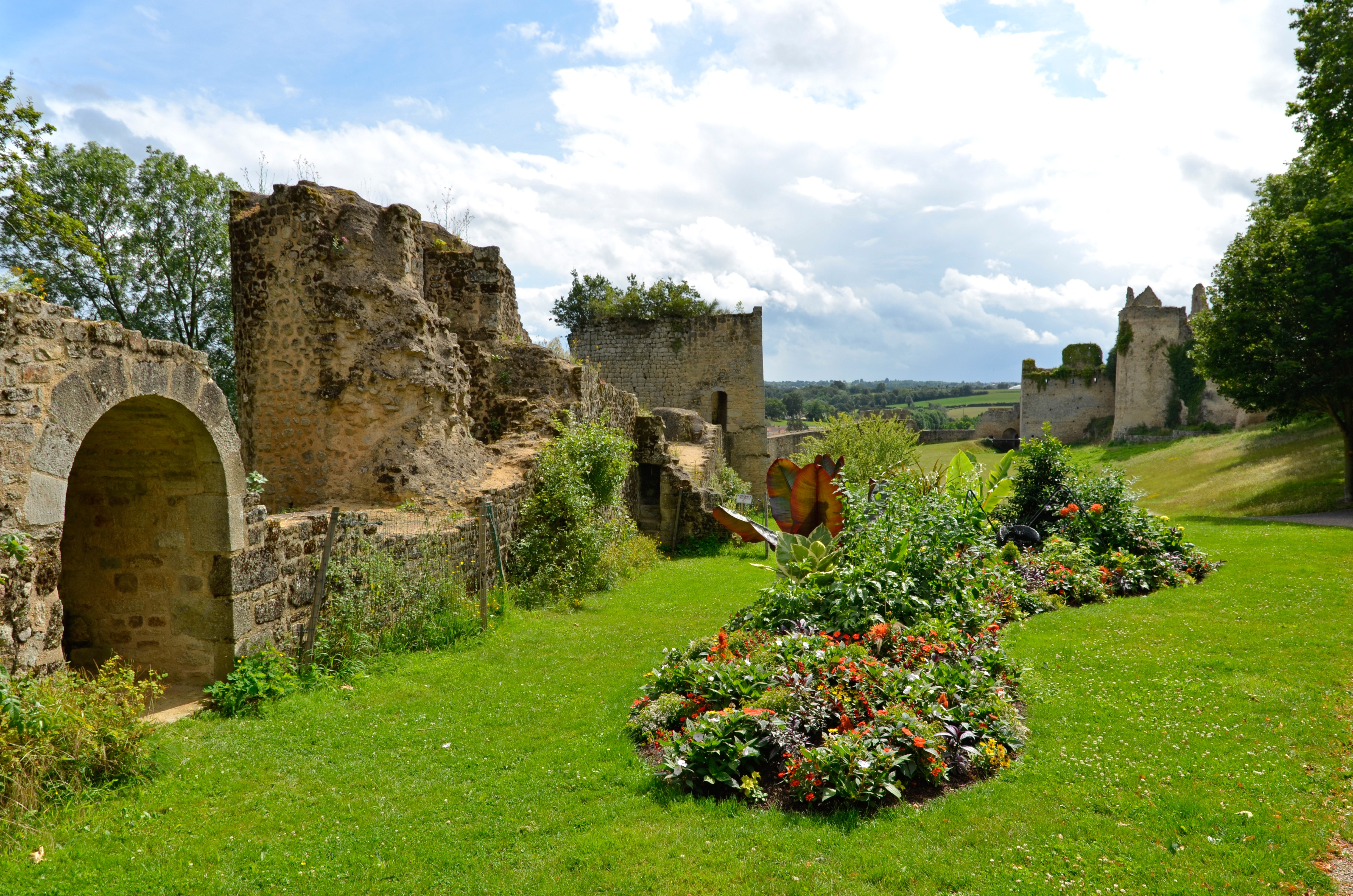 Pelouse verte avec par terre fleurie devant les vestiges du château de Bressuire 