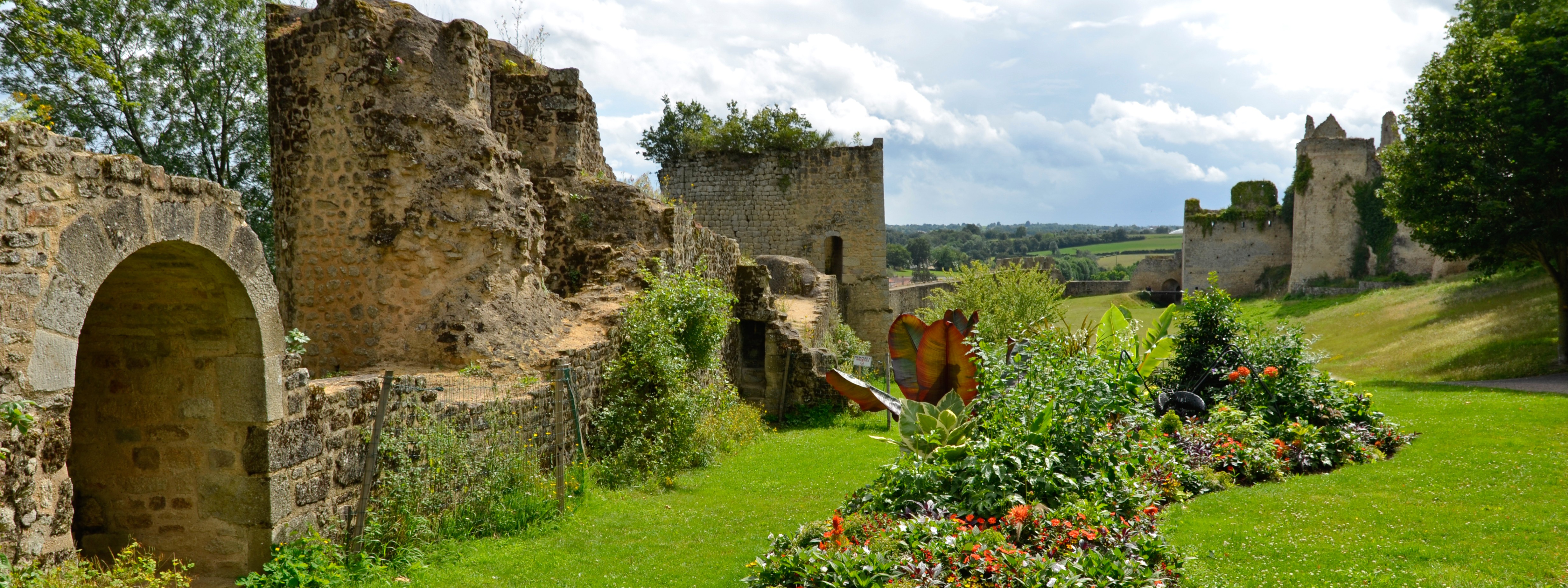 Pelouse verte avec par terre fleurie devant les vestiges du château de Bressuire 