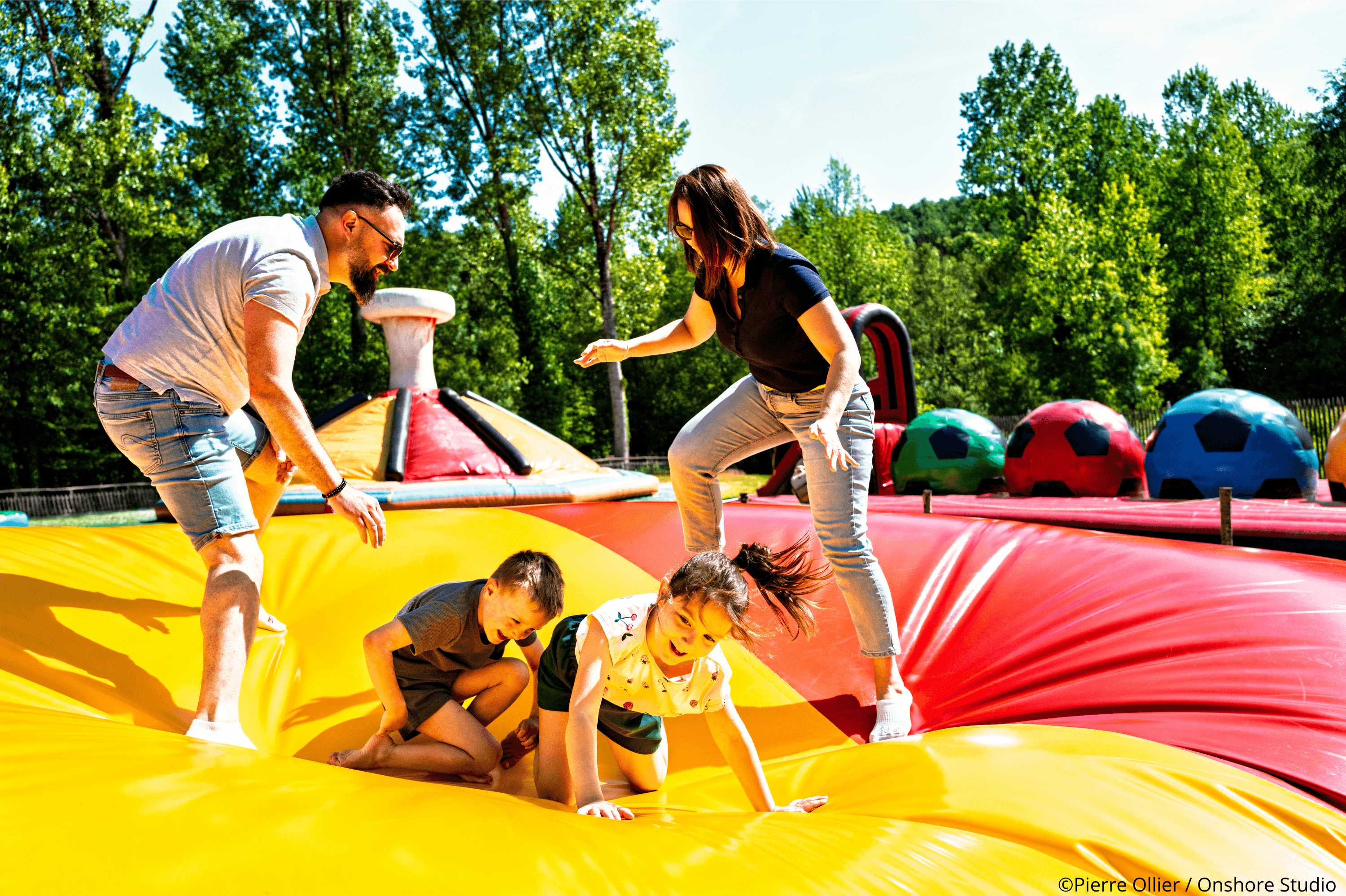 Une famille avec les parents et enfants qui s’amusent sur des jeux gonflables aux parc de Pierre Brune