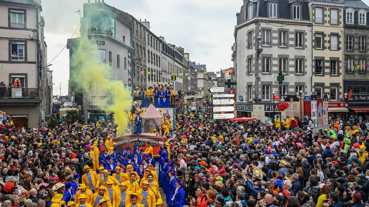 Carnaval de Granville, foule colorée avec des animations sur chars et de la fumée jaune dans les rues.
