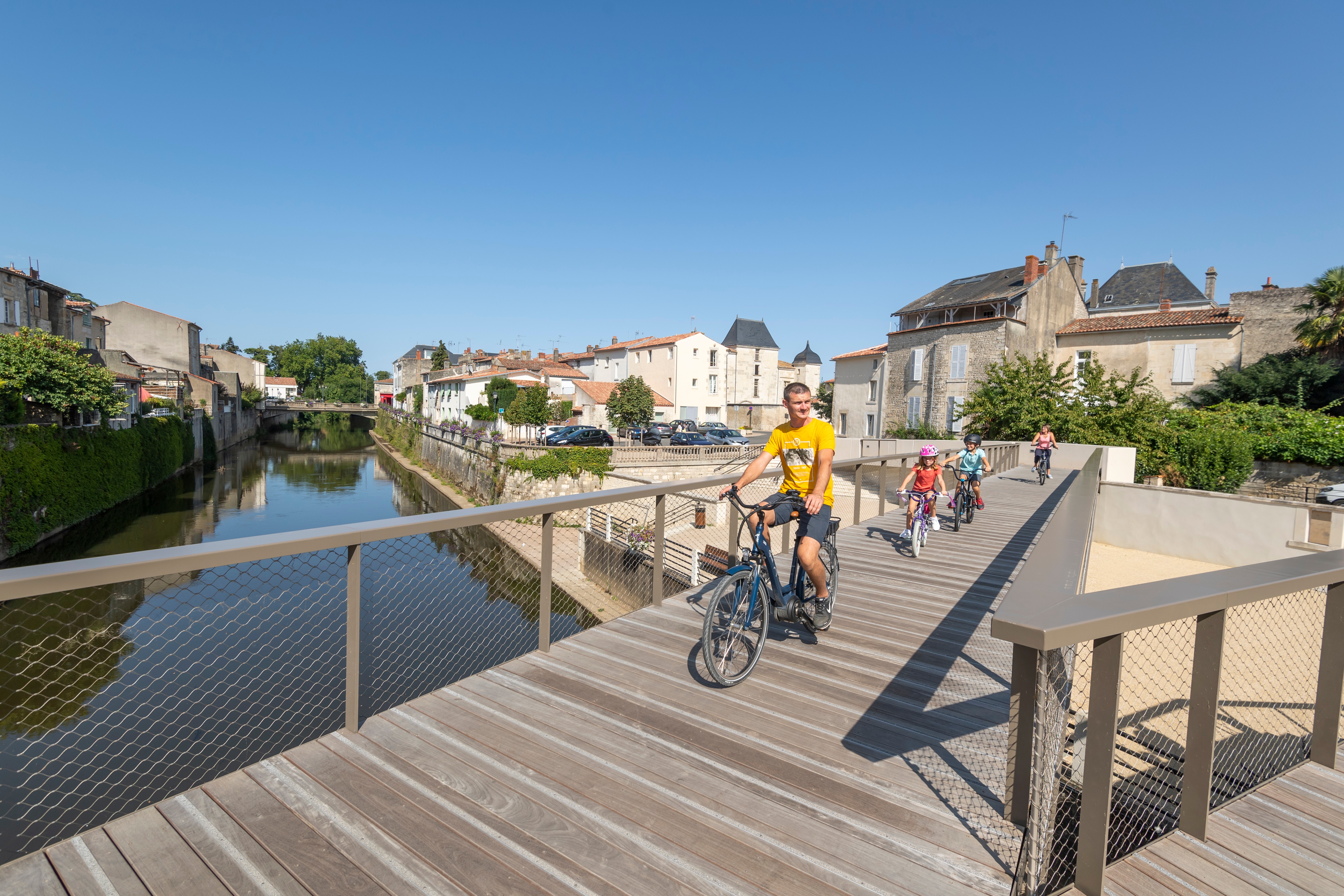Une famille qui traverse un pont à vélo au dessus la rivière de la Vendée