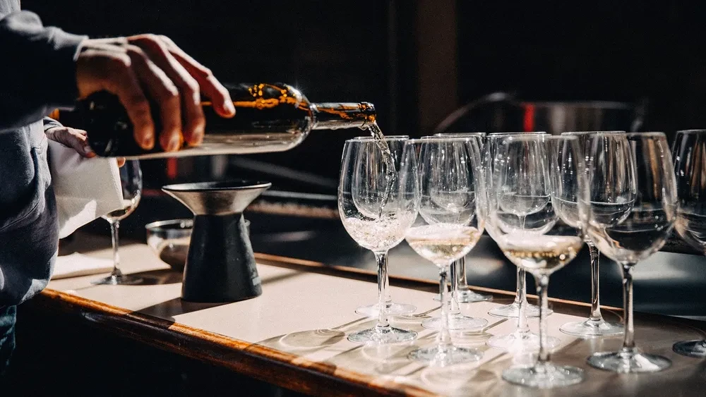 Personne servant du vin dans plusieurs verres alignés lors d'une dégustation