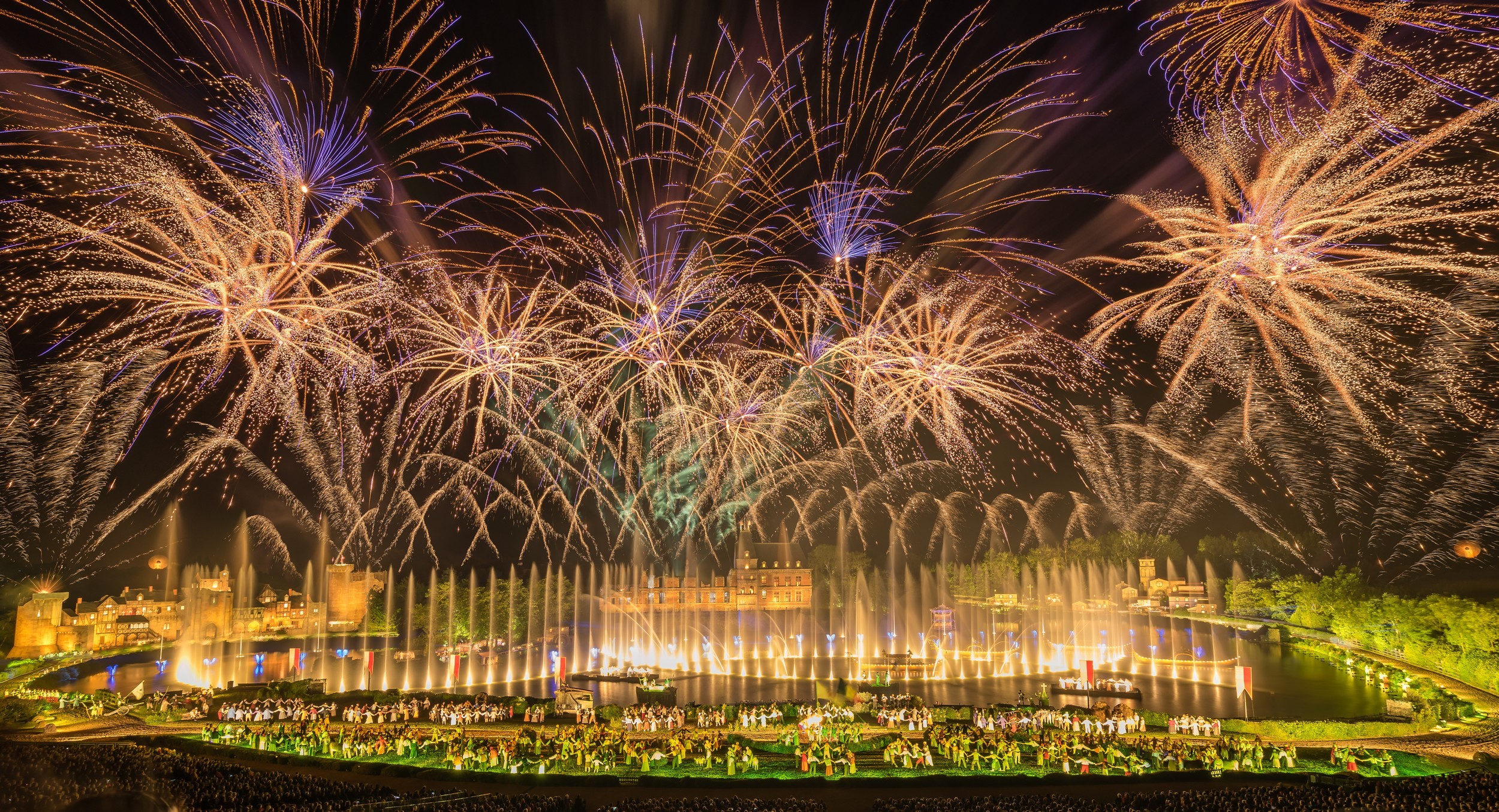 Spectacle nocturne de la Cinéscénie avec feu d’artifice, jeux d’eau et de lumières et scénographie jouée par des acteurs qui danses autour du lac