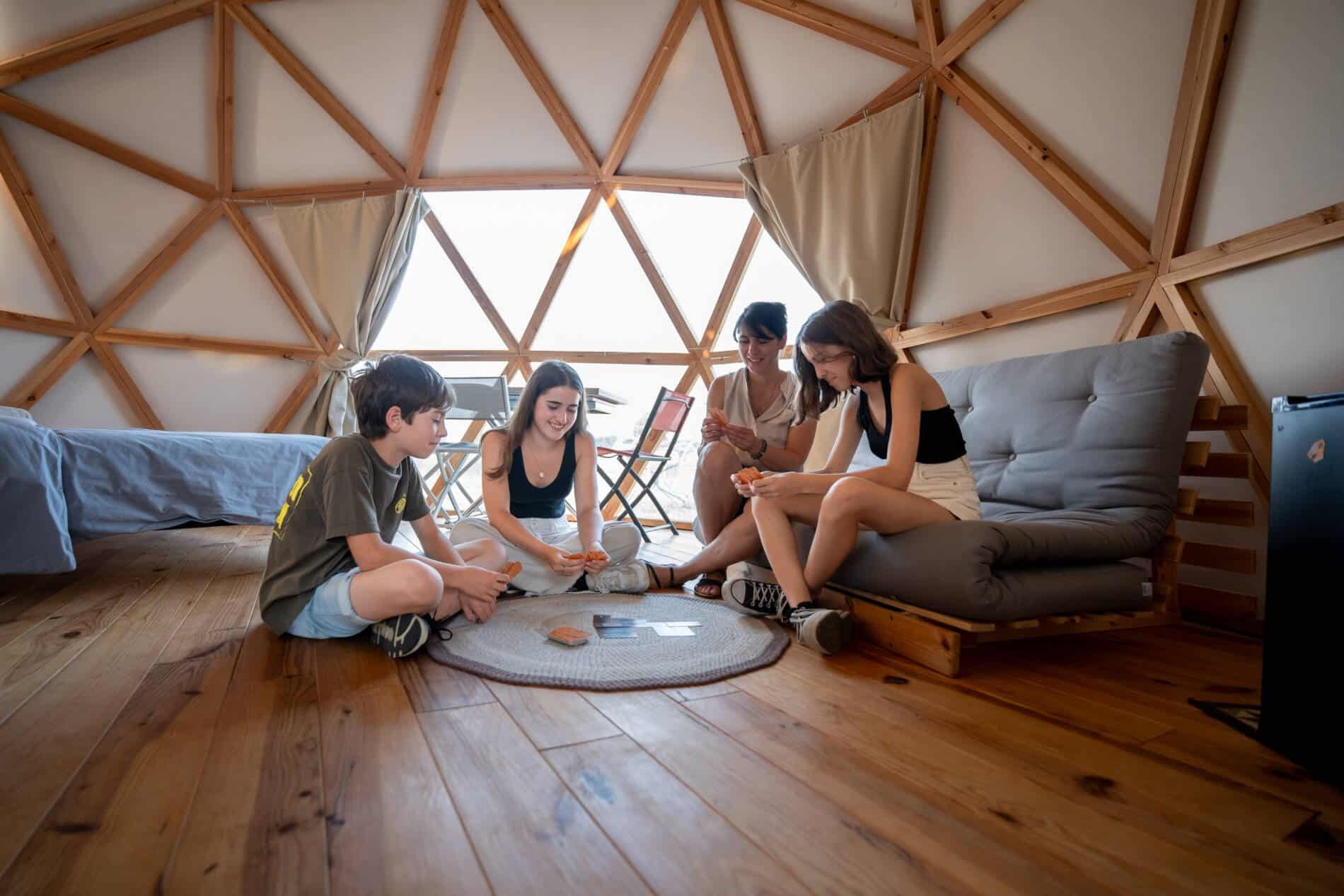 Famille jouant ensemble à l'intérieur d'un dôme en bois avec une décoration chaleureuse.