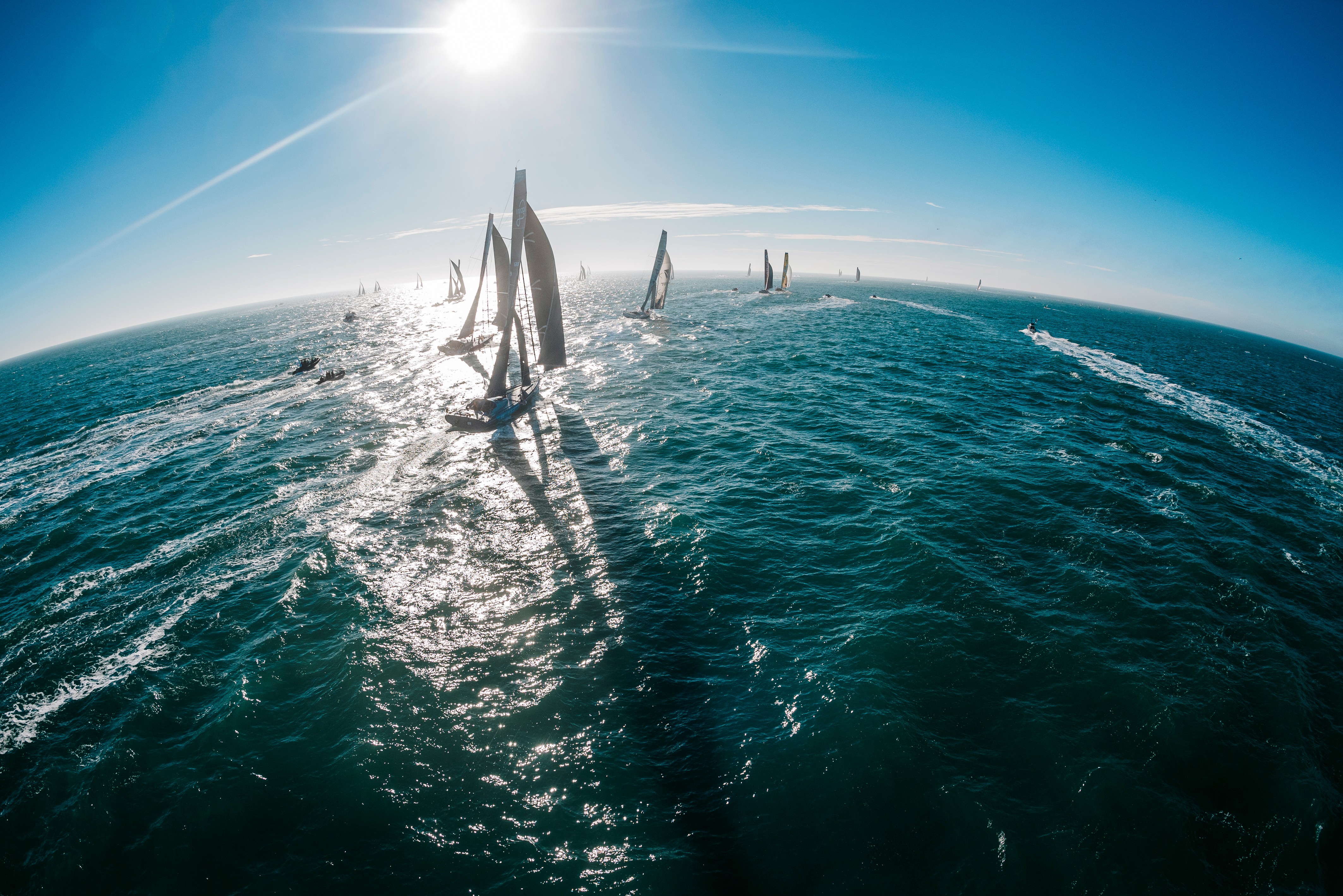 Vue du ciel sur les voiliers imoca du Vendée Globe amarrés aux pontons sur l’océan.