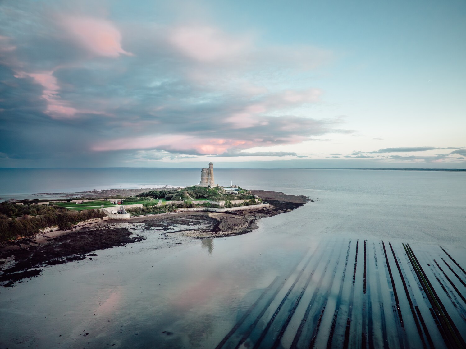 Tour Vauban de l'Ile Tatihou, parc à huitres, vue du ciel couleurs bleu et rose avec quelques nuages, ambiance féérique