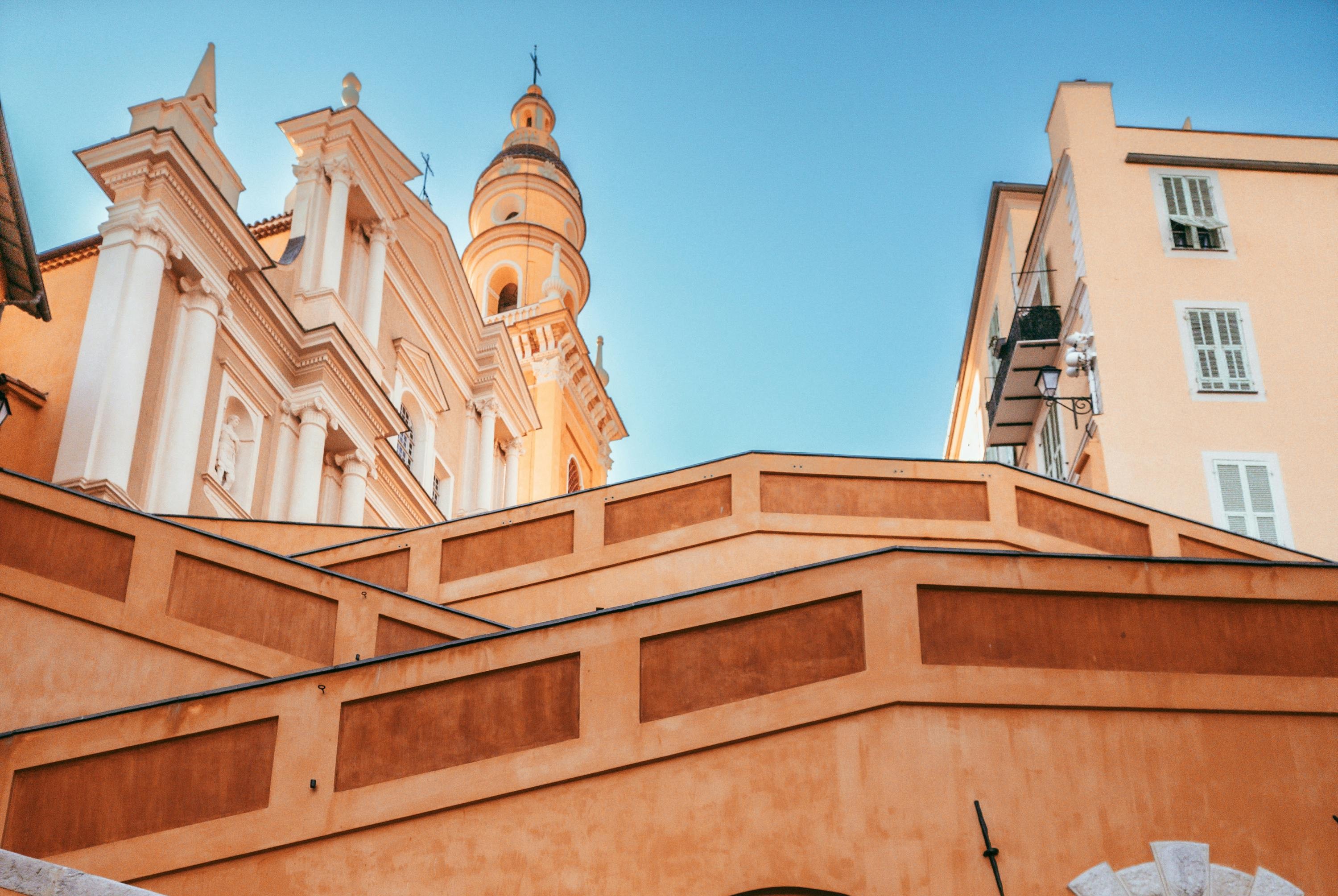 La Basilique Saint-Michel Archange et ses couleurs emblématiques de Menton vue depuis le bas des escaliers