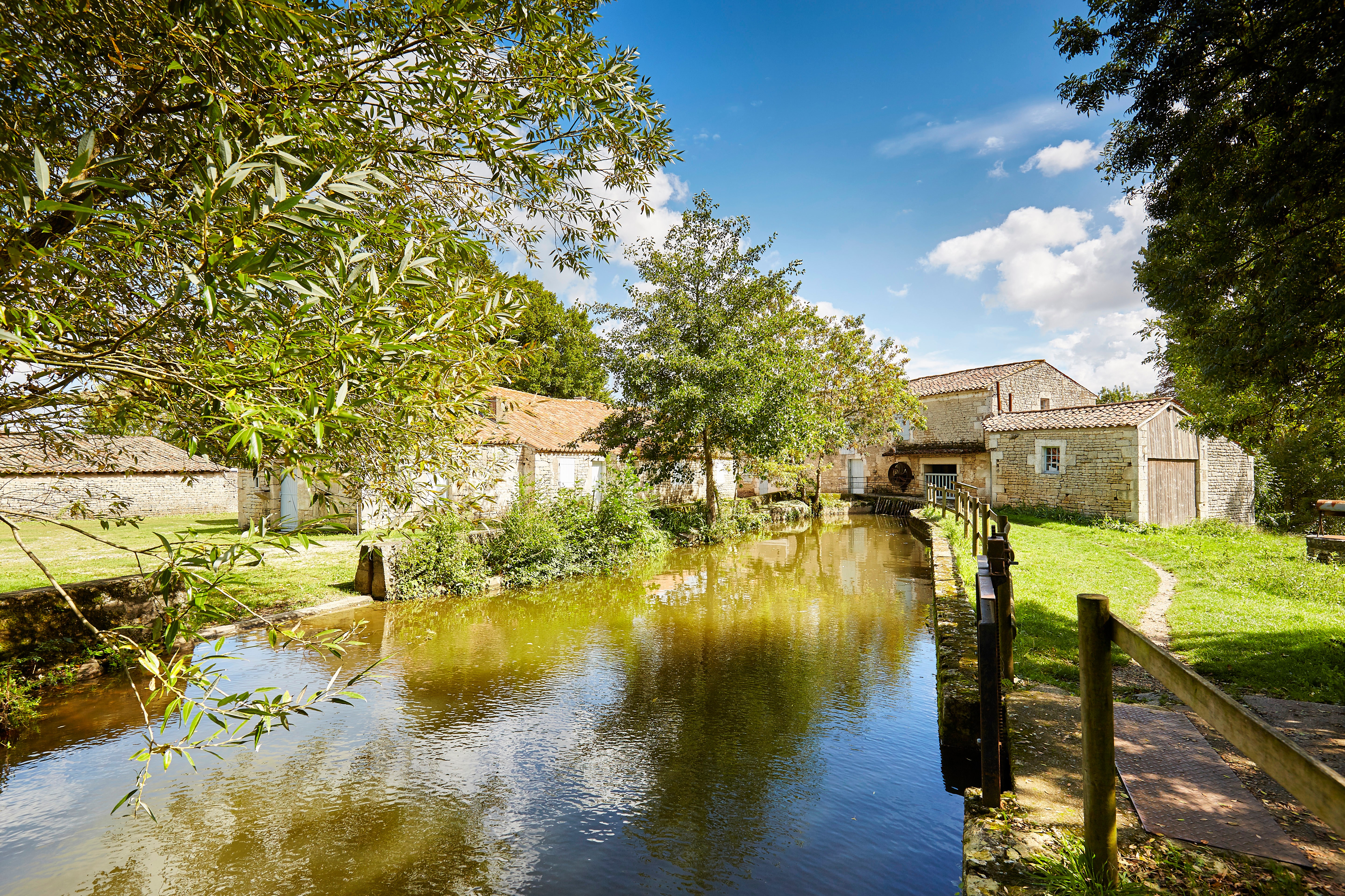 Dans un cadre verdoyant, la rivière de l’Autize mène à la maison de la Meunerie, moulin en pierre proche de l’abbaye de Nieul sur l’Autize