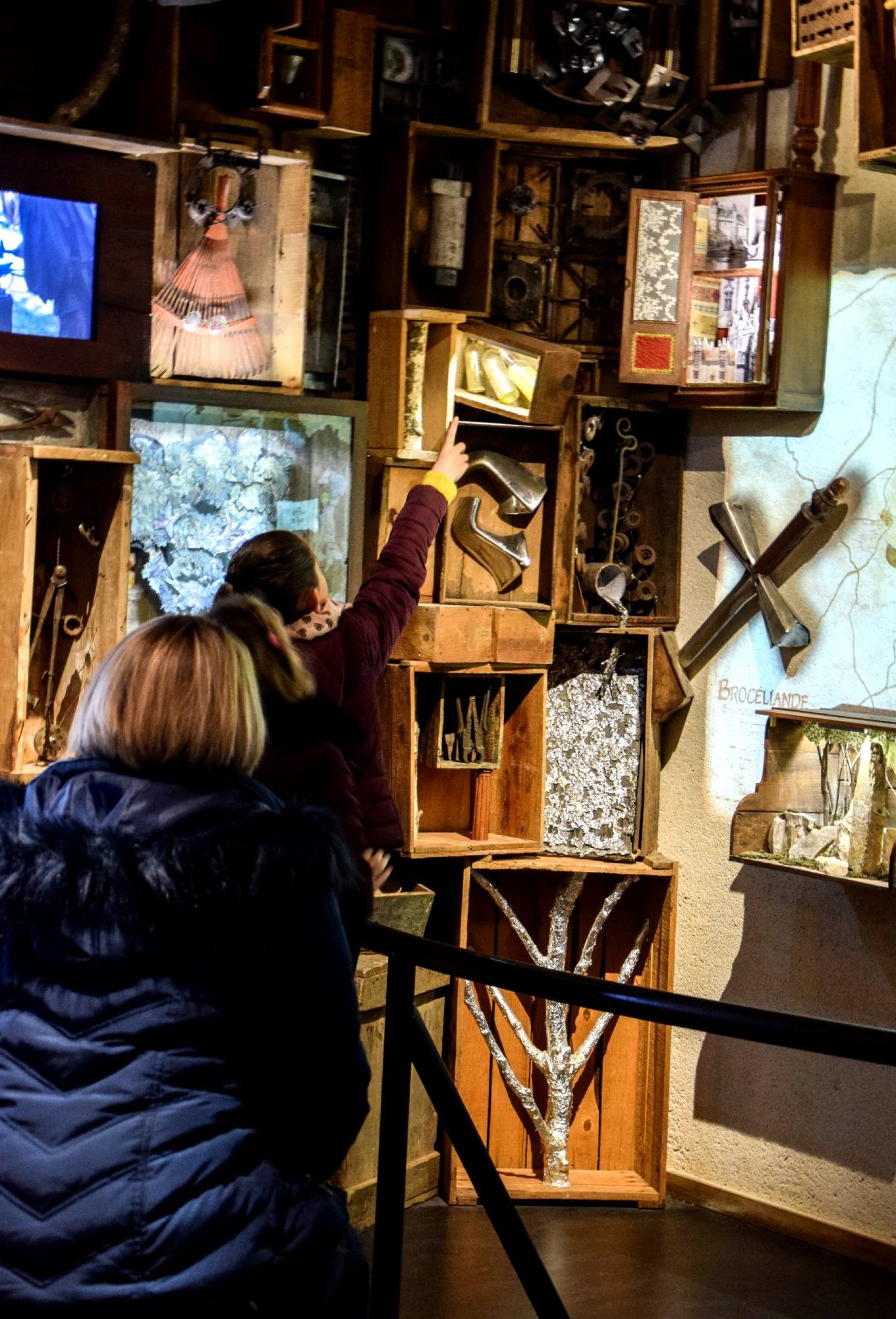 Visiteurs observant des objets exposés dans la salle des Destinations à la Porte des Secrets en Brocéliande