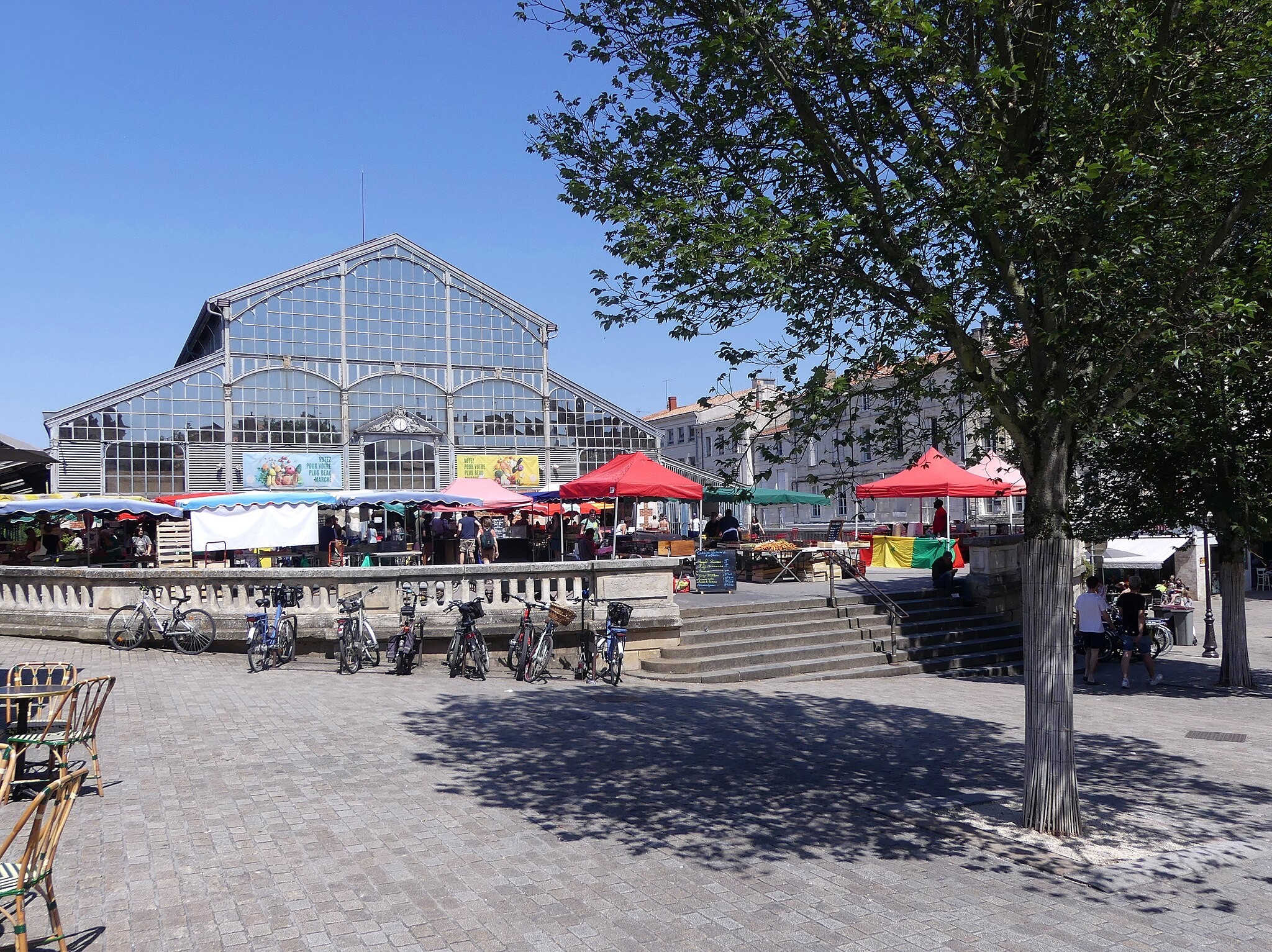 Les Halles de Niort et ses verrières avec le Donjon de Niort en arrière plan et des vélos au pied des marches.