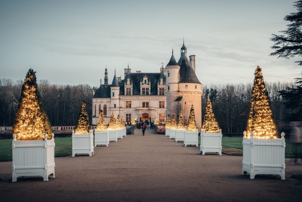 Entrée illuminée du château de Chenonceau, décorée pour Noël avec des sapins lumineux alignés