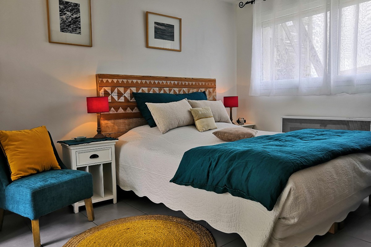 Chambre confortable et décorée avec goût dans une location Clévacances, équipée d'un lit double, de coussins colorés et d'une ambiance chaleureuse