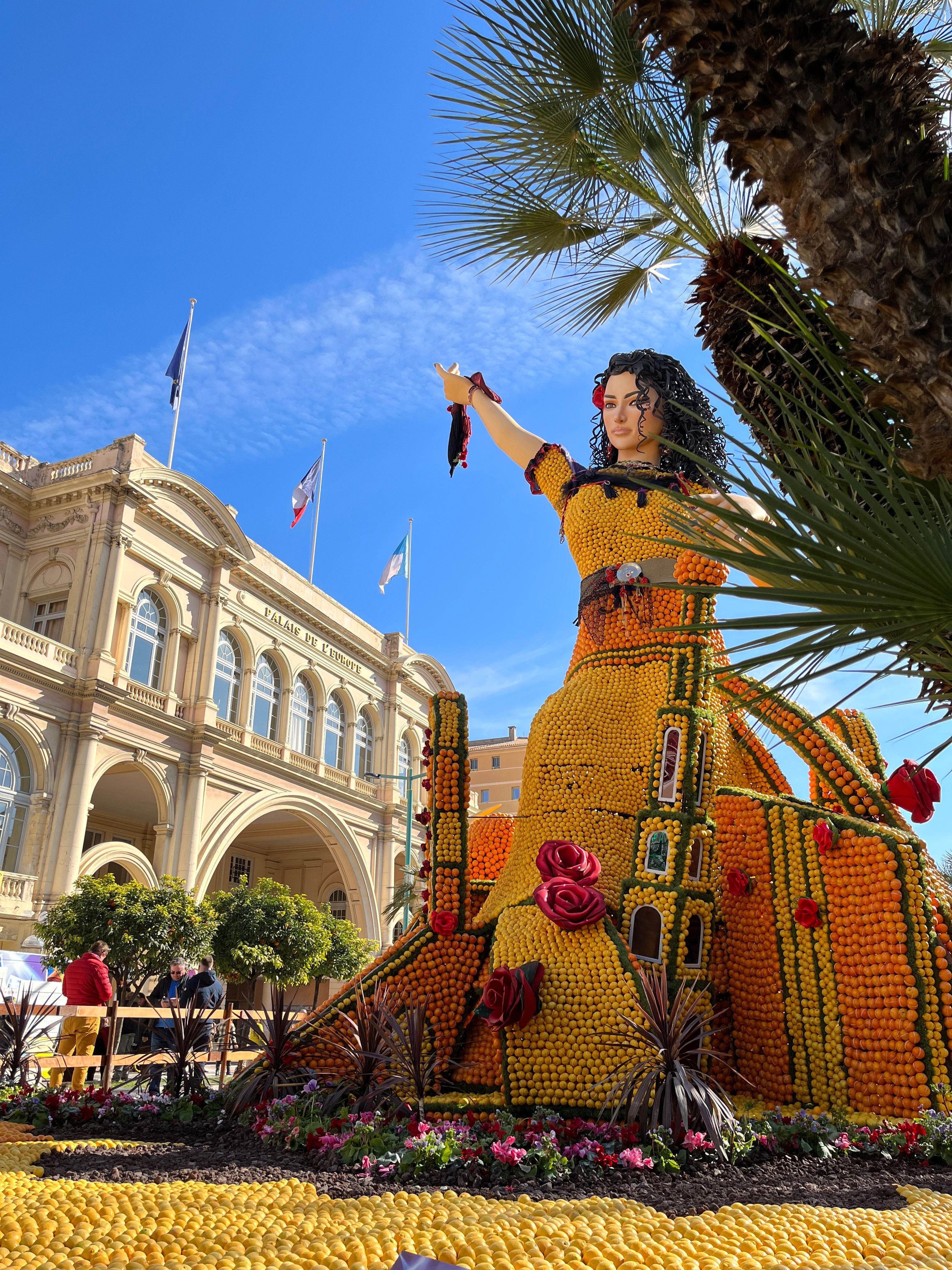 Exposition des oeuvres de la fête du citron devant les bâtiments de la ville de Menton et les palmiers sous un ciel bleu azur 