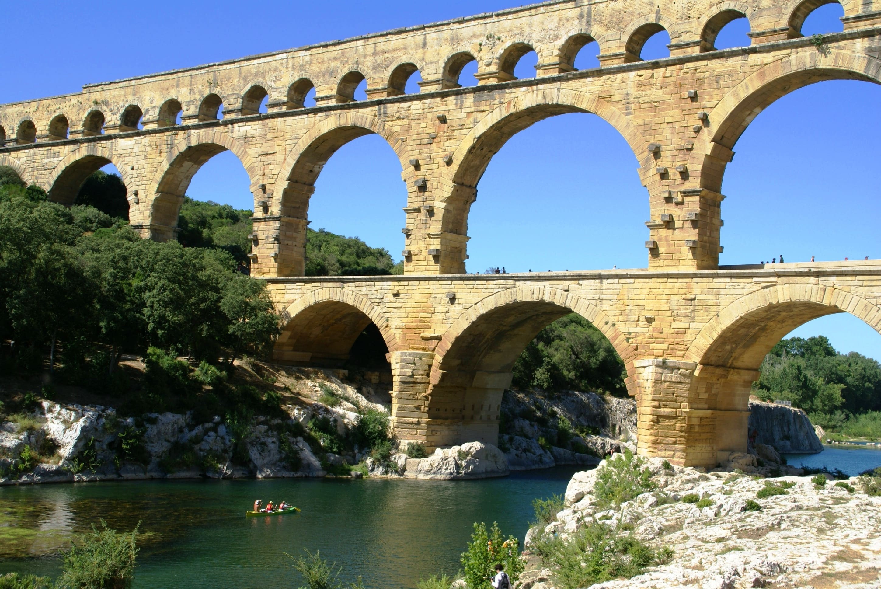 Un canoë descend la rivière Gardon et passe sous le Pont du Gard