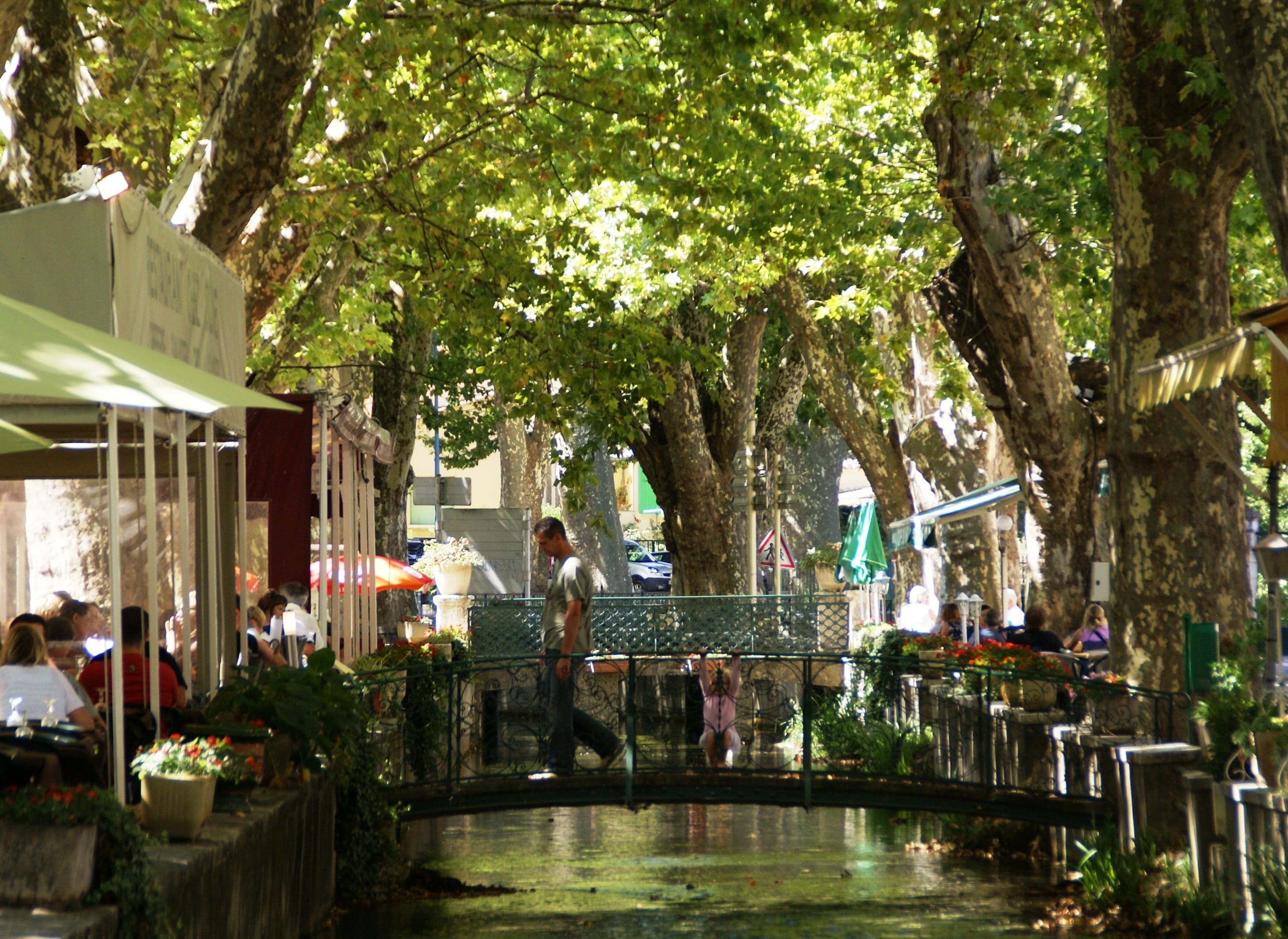 Le canal ombragé de platanes et les terrasses de restaurant de Goudargues dans le Gard