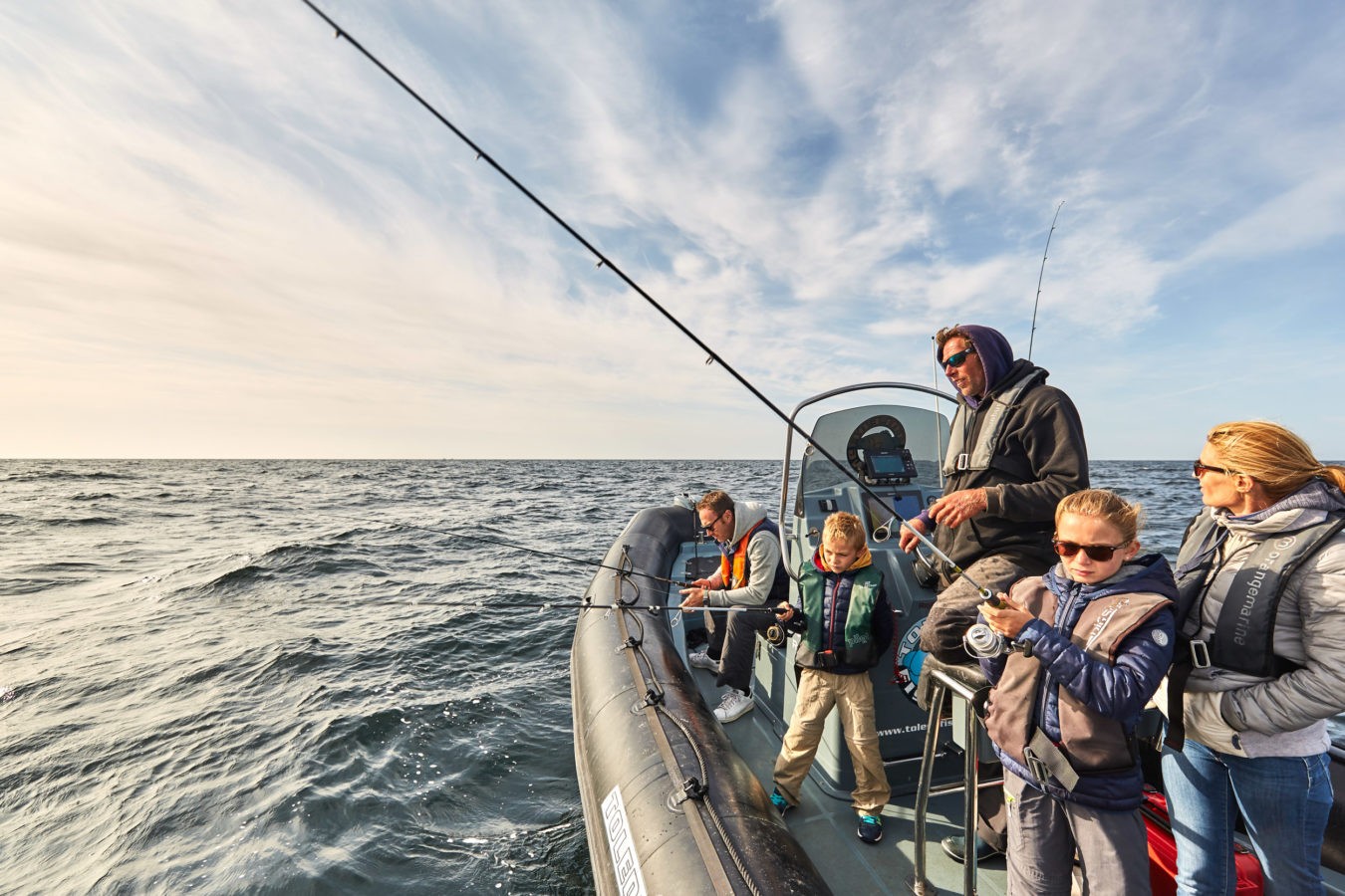 Famille pêchant ensemble sur un bateau en mer sous un ciel dégagé