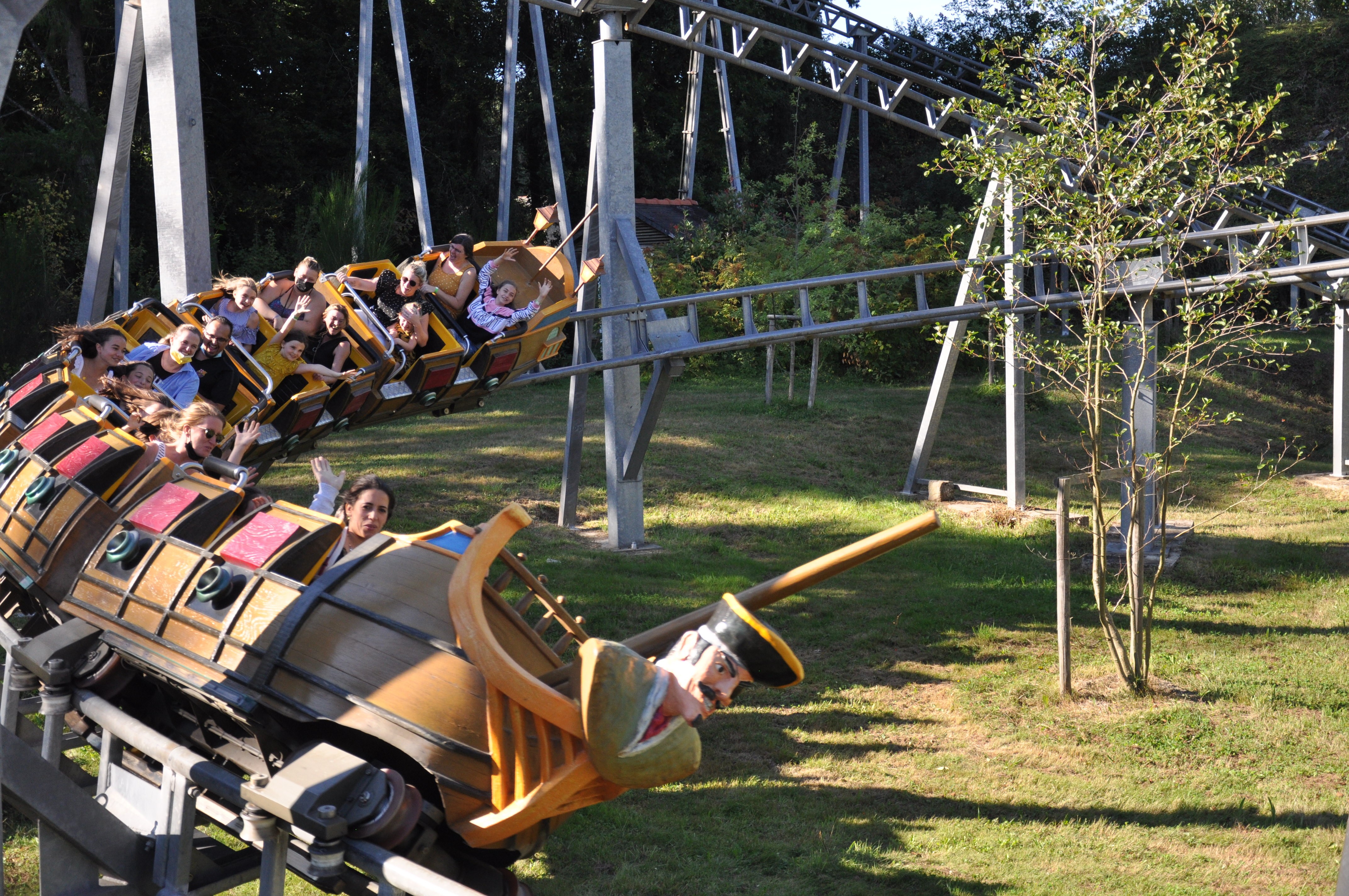 Personnes profitant d'une attraction en montagnes russes à bord de wagons en forme de bateau