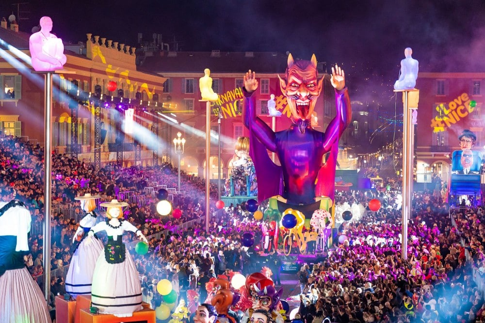 Spectacle nocturne du Carnaval de Nice avec chars illuminés et foule en fête.