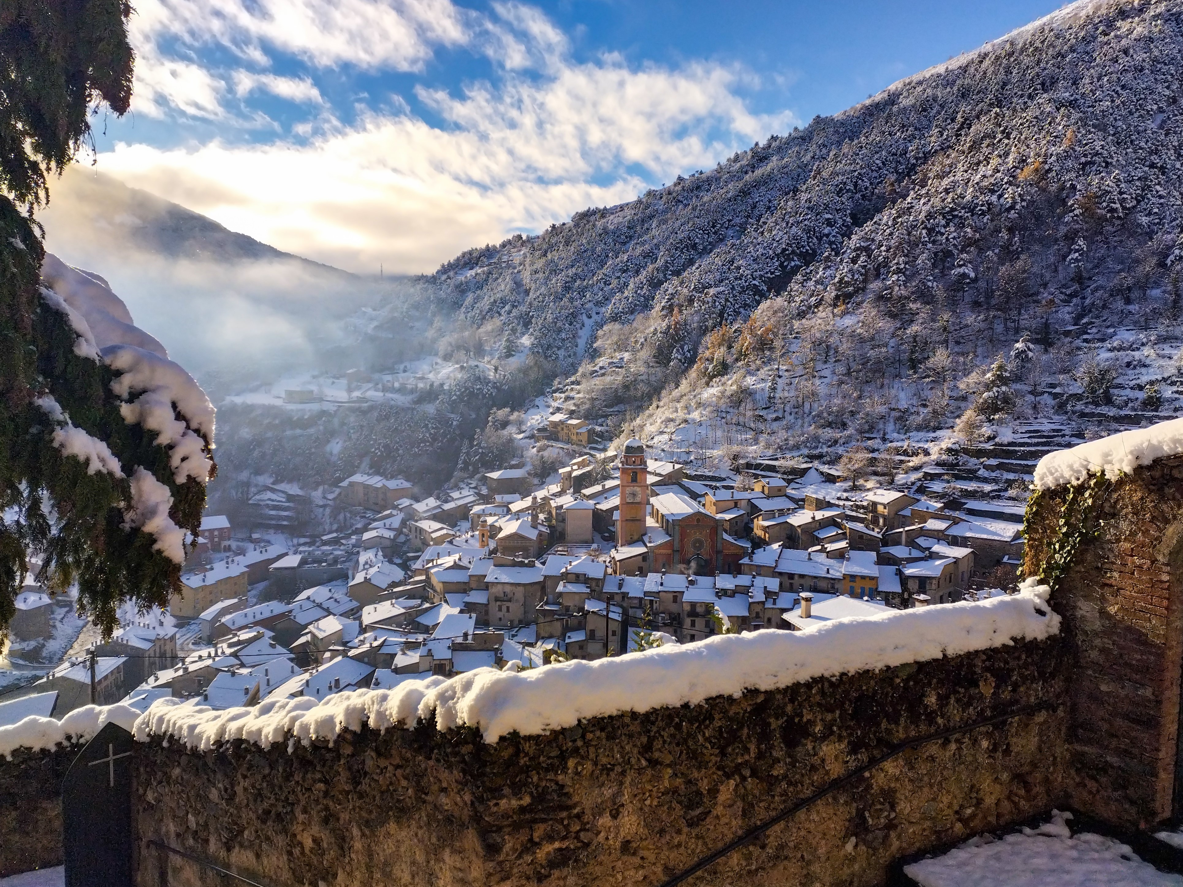 Vue panoramique du village de Tende, porte d’entrée de la vallée des Merveilles, un paysage enneigé avec une lumière d’hiver et des nuages en basse altitude