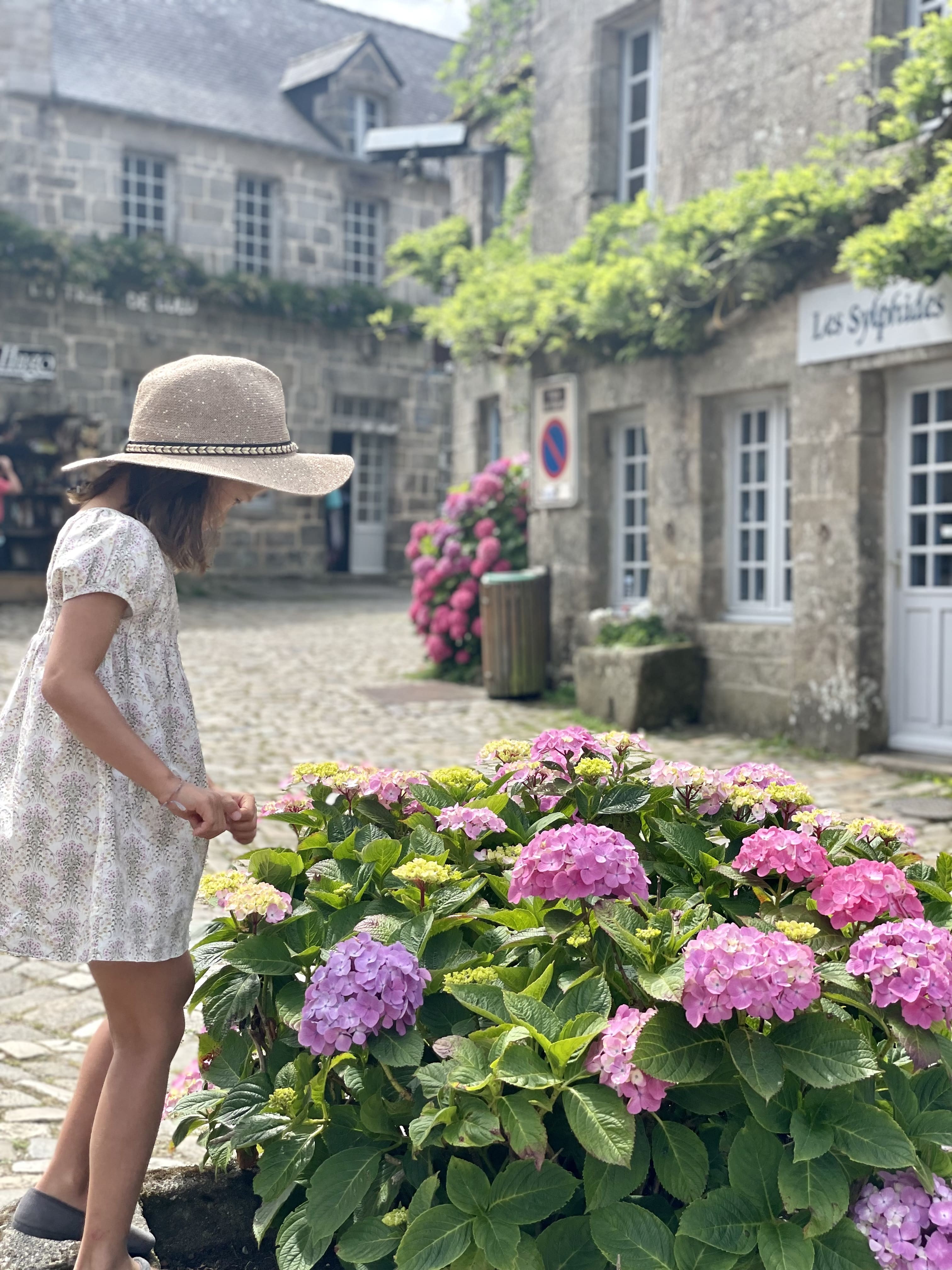 Petite fille avec chapeau auprès d’hortensia rose à Locronan