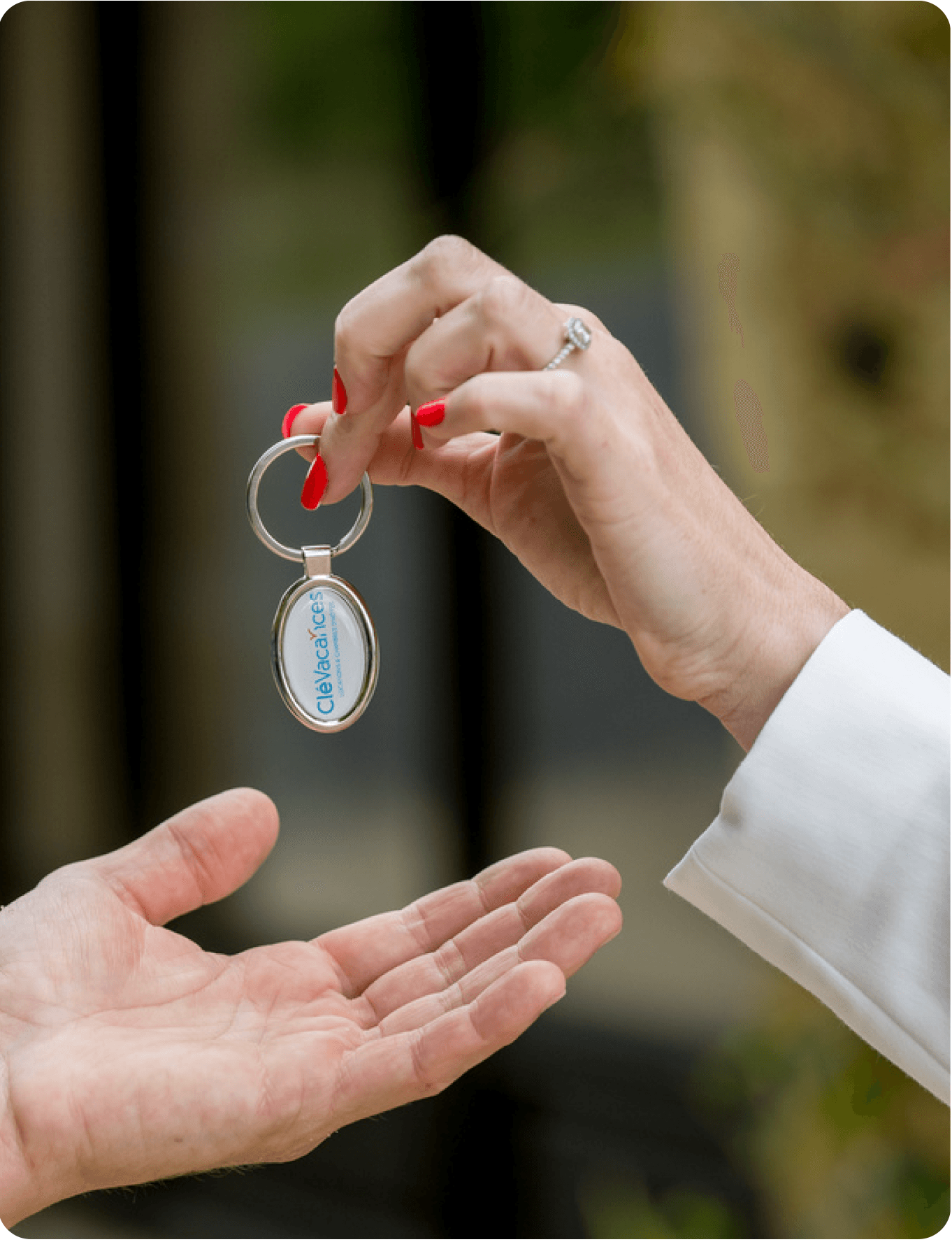 Photo cadrée sur deux mains se transmettant un porte-clés avec le logo de Clévacances.