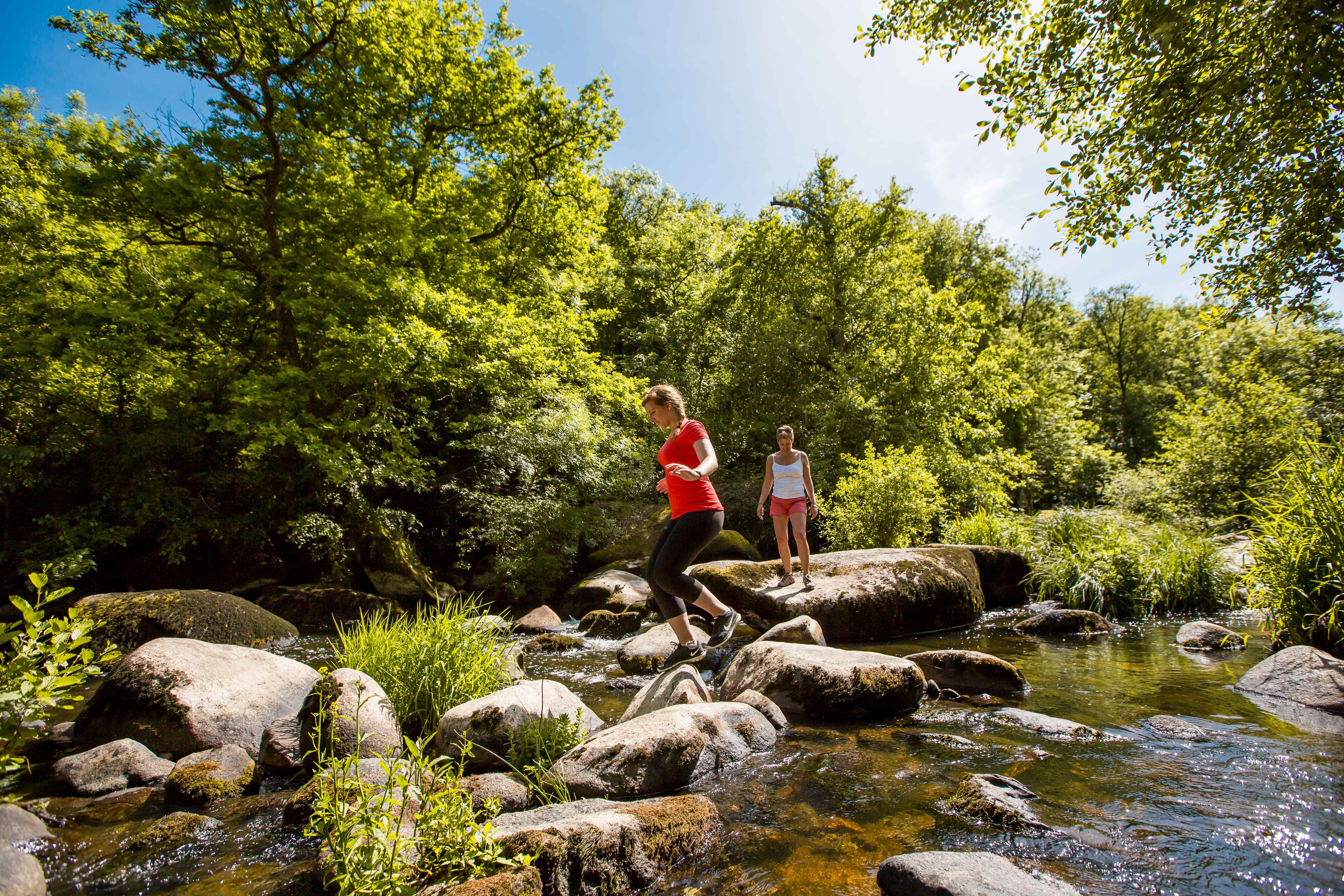 Deux femme qui pratiquent la randonnée en traversant la rivière de Piquet depuis les Rochers 