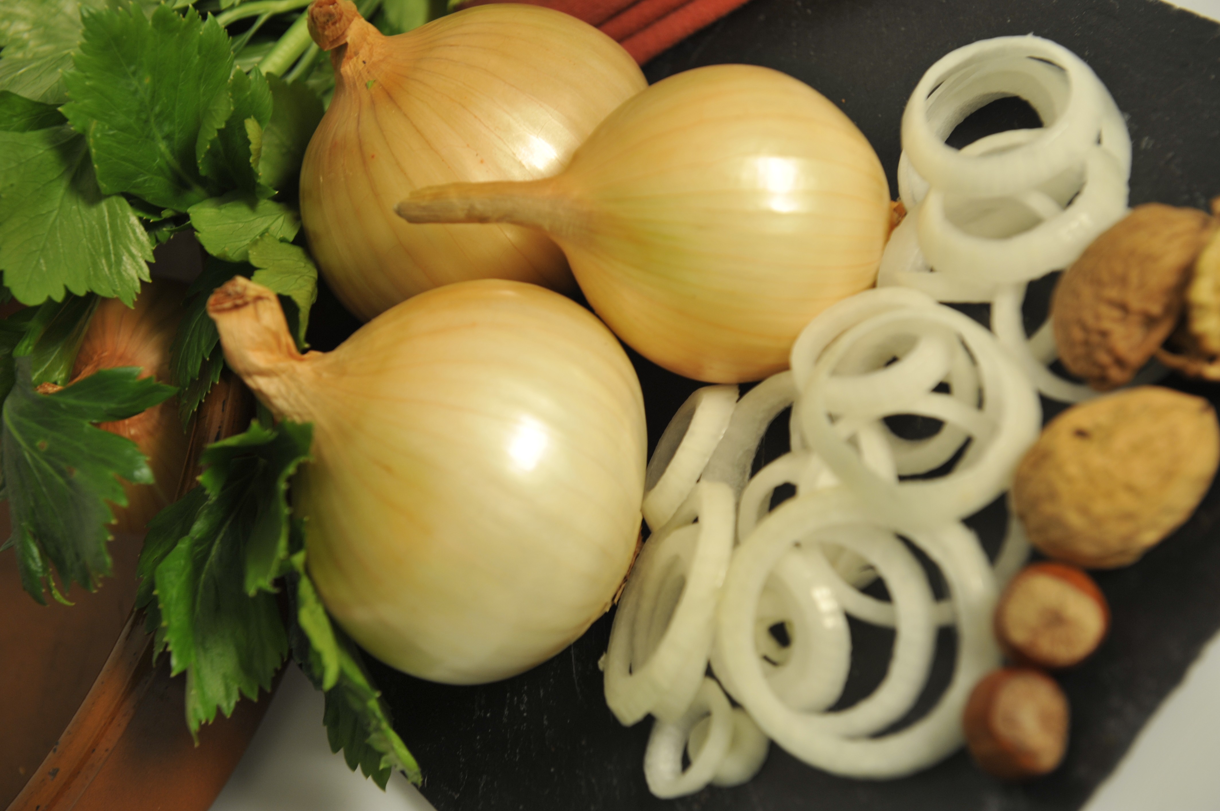 Assiette de présentation avec des oignons entiers, des oignons découpés, des noix et des noisettes