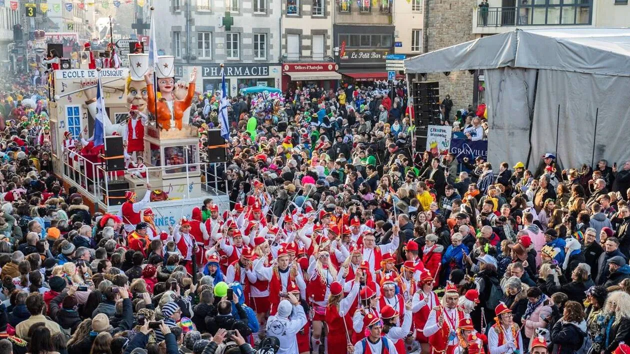 Défilé festif au Carnaval de Granville avec des costumes rouges et blancs, entouré par une foule animée.