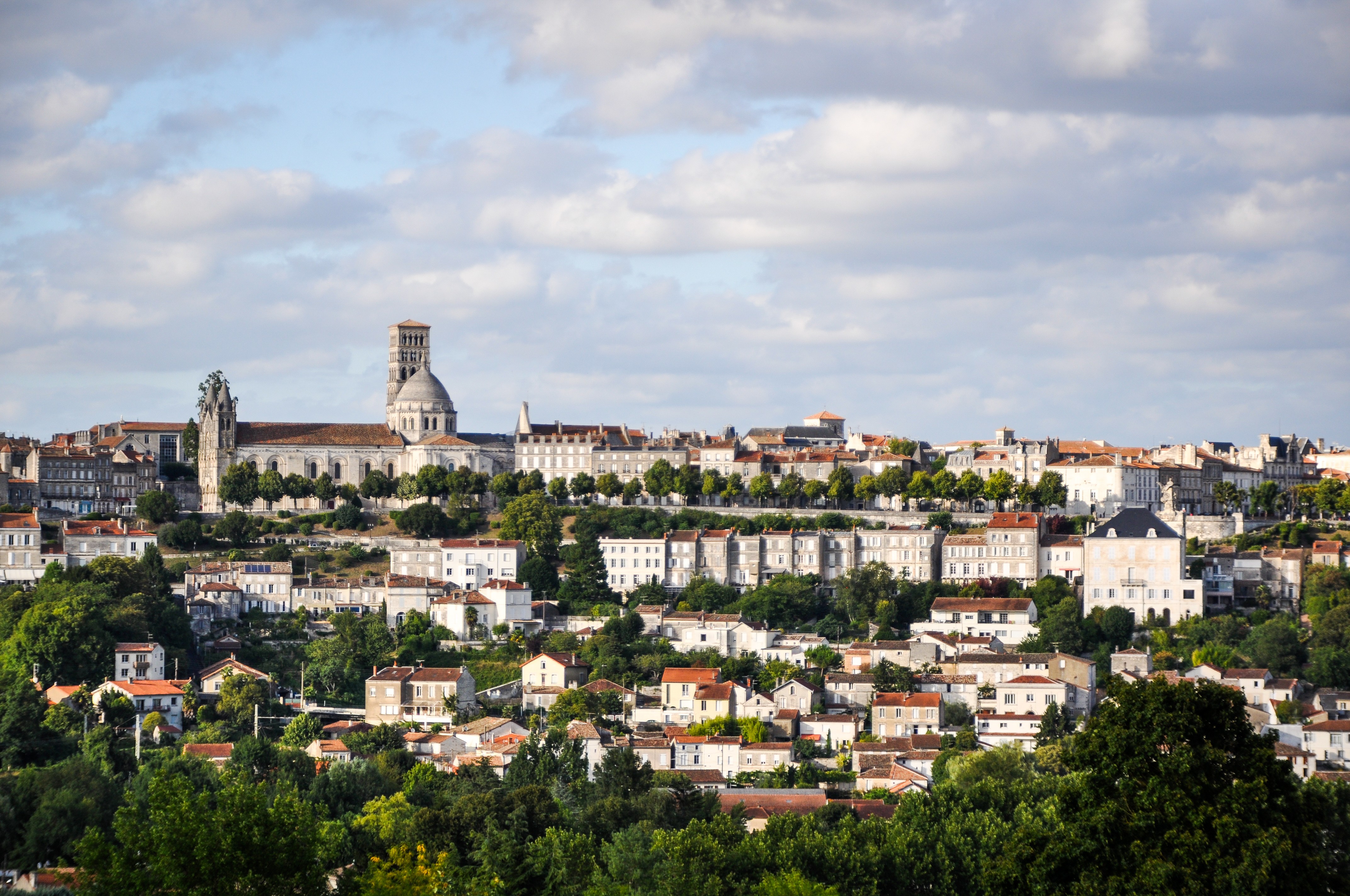 Vue panoramique de la ville d'Angoulême avec ses maisons typiques et sa cathédrale sous un ciel bleu.