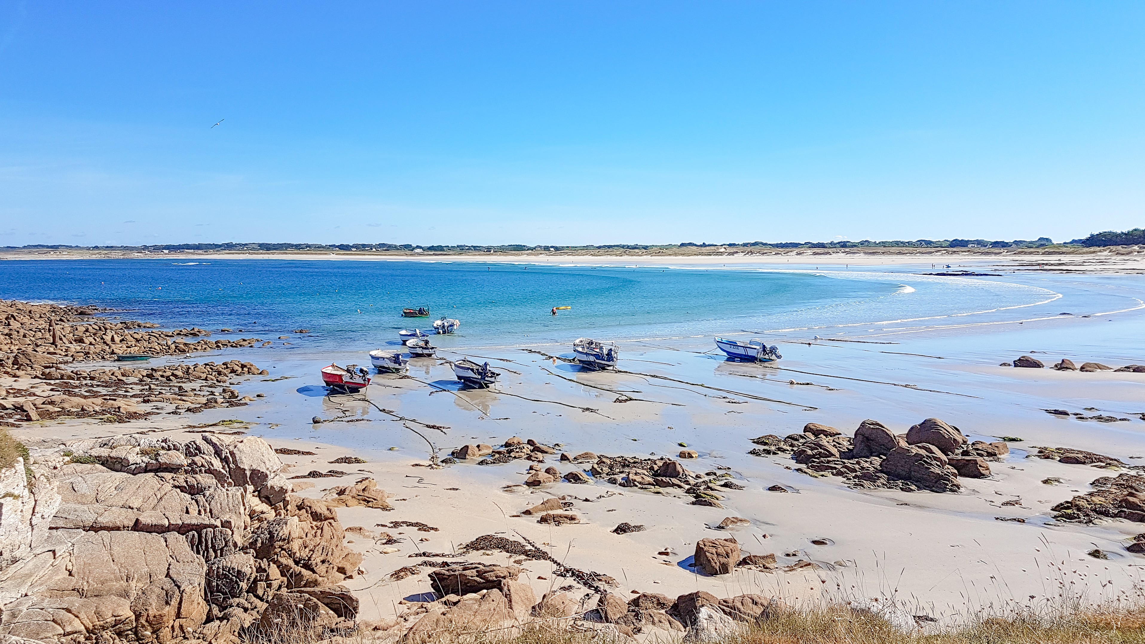 Plage avec bâteaux, rochers et mer vue depuis la dune