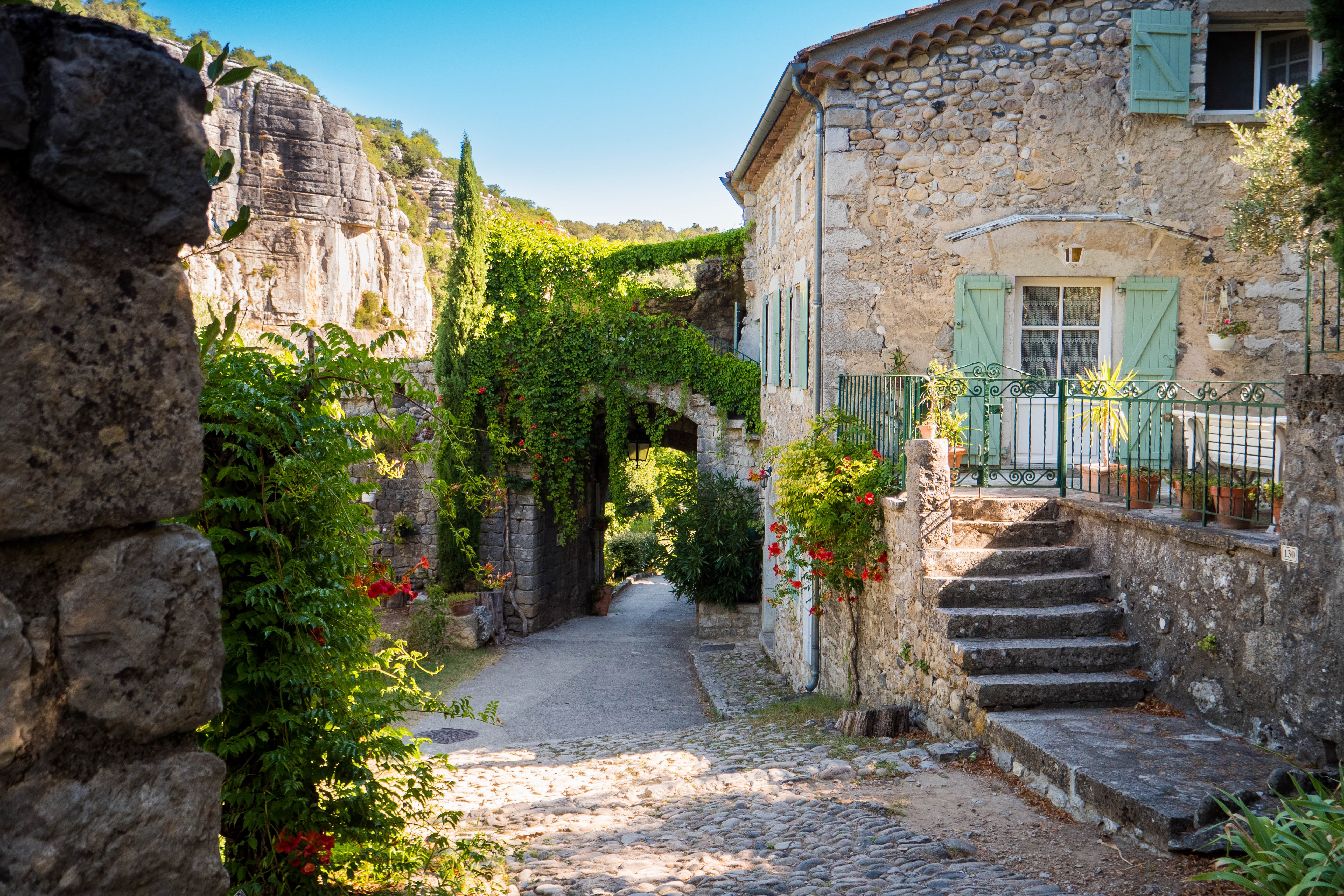 Ruelle pietonne dans le vieux village de caractère avec de belles maisons en pierres et de la végétation
