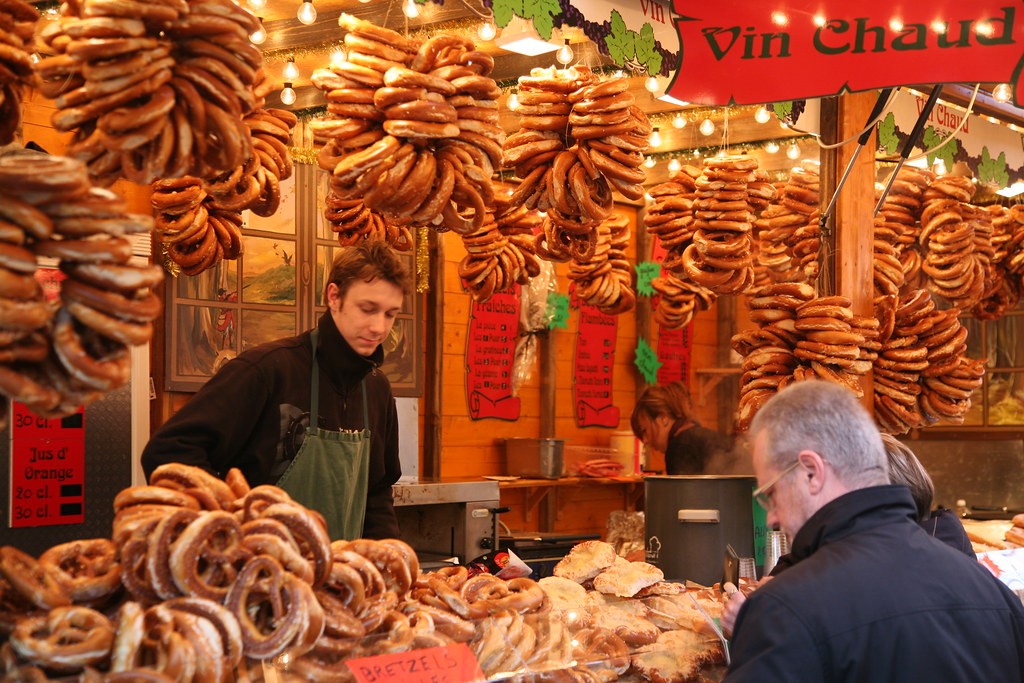 Stand de bretzels au marché de Noël en Alsace, ambiance festive avec lumières et vin chaud.