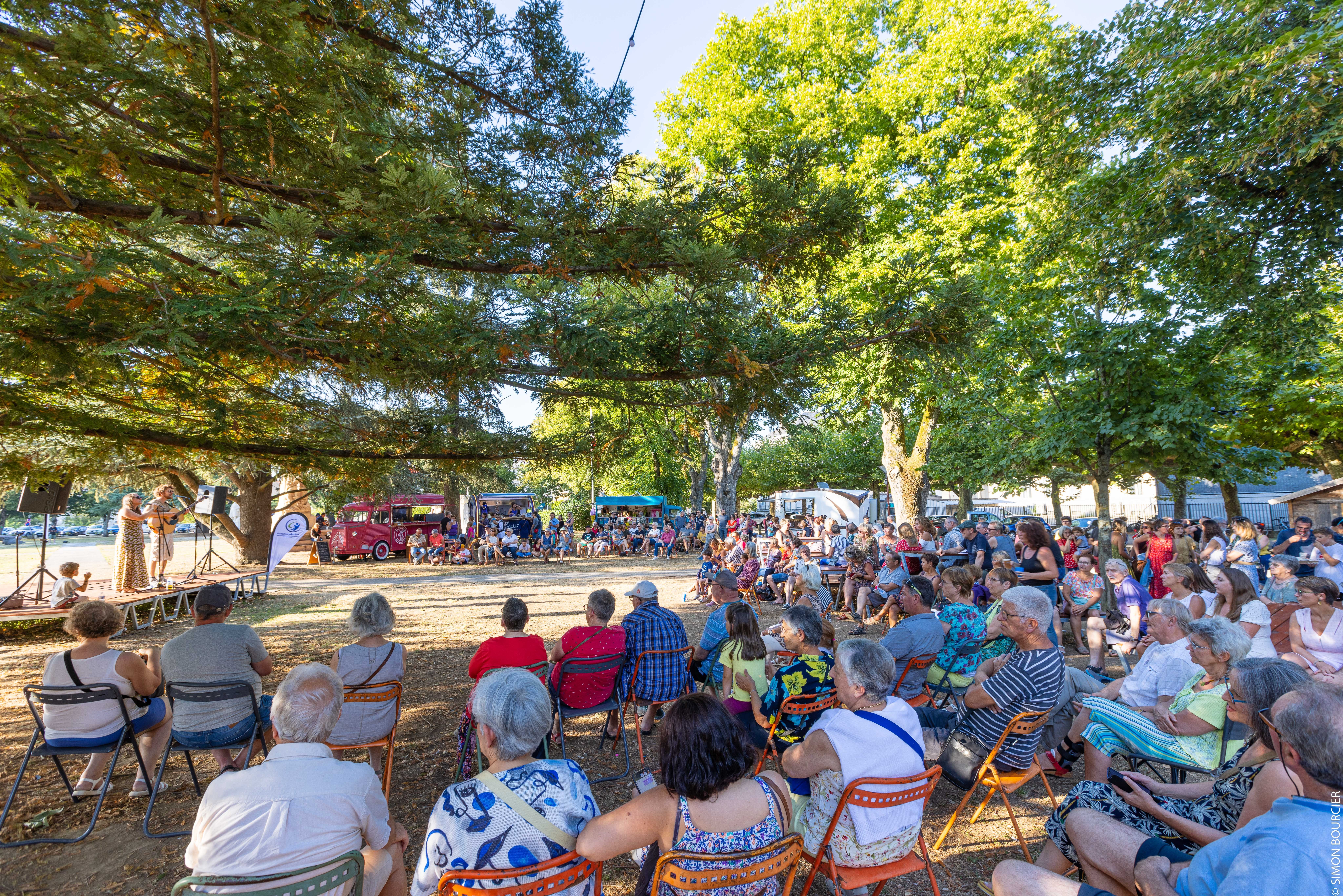 Spectateurs qui assistent à un concert dans un parc en pleine nature sous les arbres