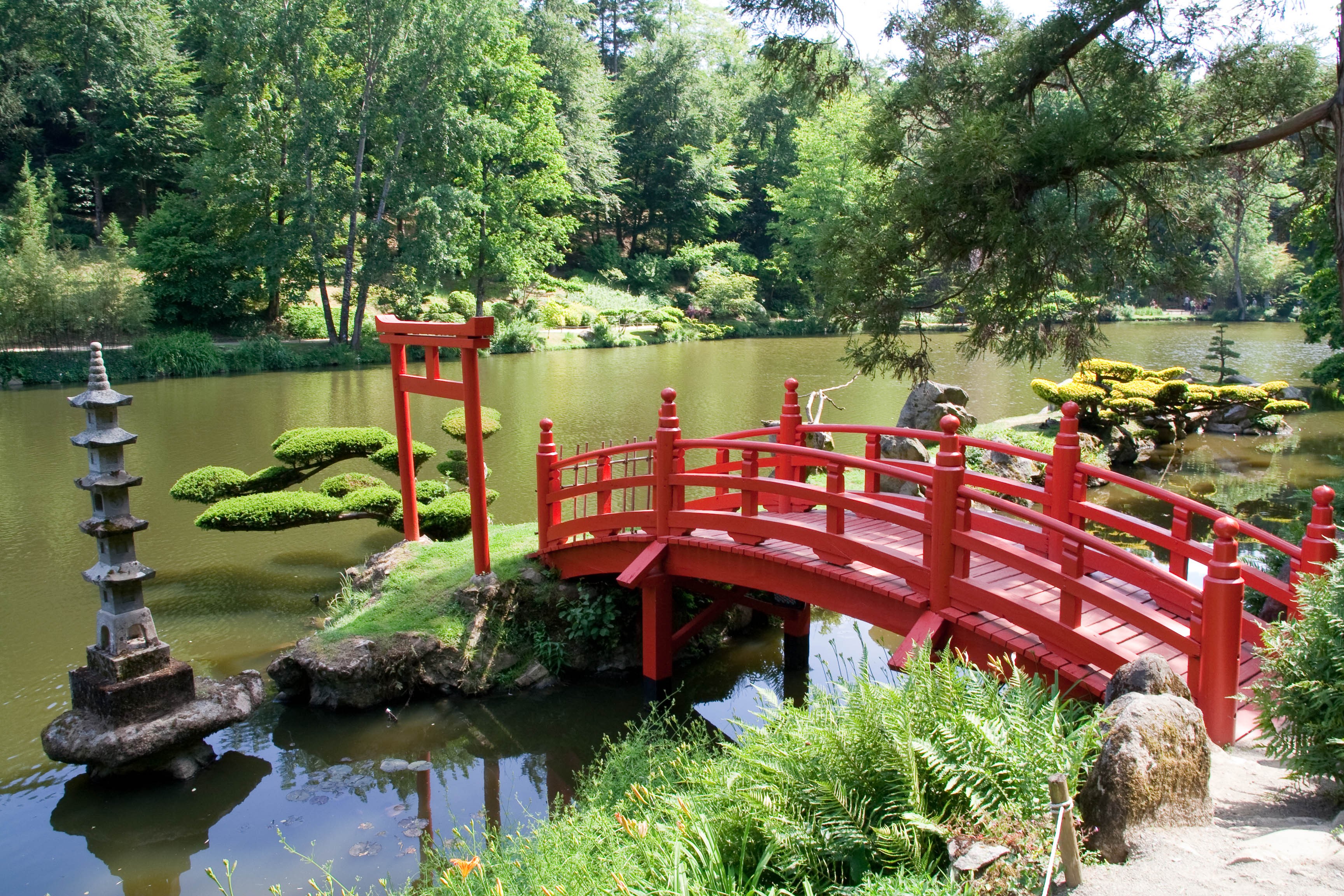 Jardin japonais du parc oriental de Maulévrier avec un pont rouge menant sur un petit îlot et passant au-dessus la rivière de la Moine.
